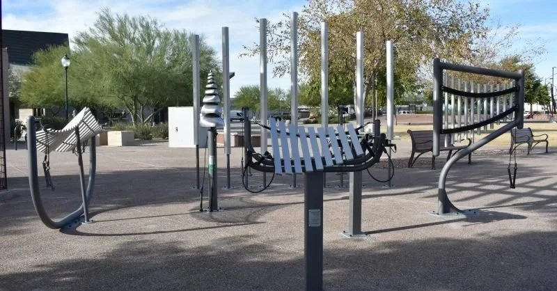 Outdoor park with benches, art installations, and trees in the background