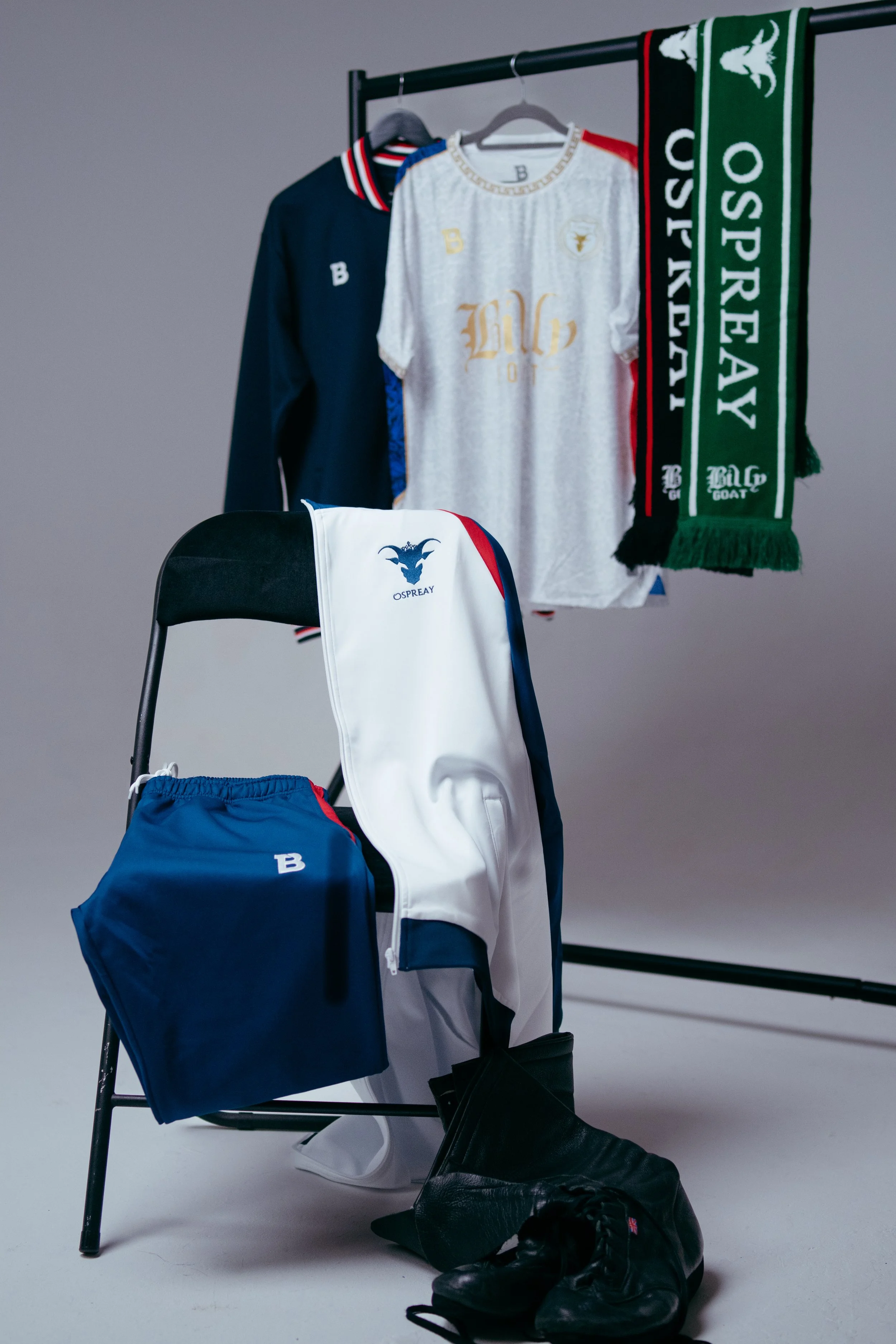Sportswear and accessories including jerseys, a scarf, shorts, and gloves, displayed on a chair and hanging on a rack.