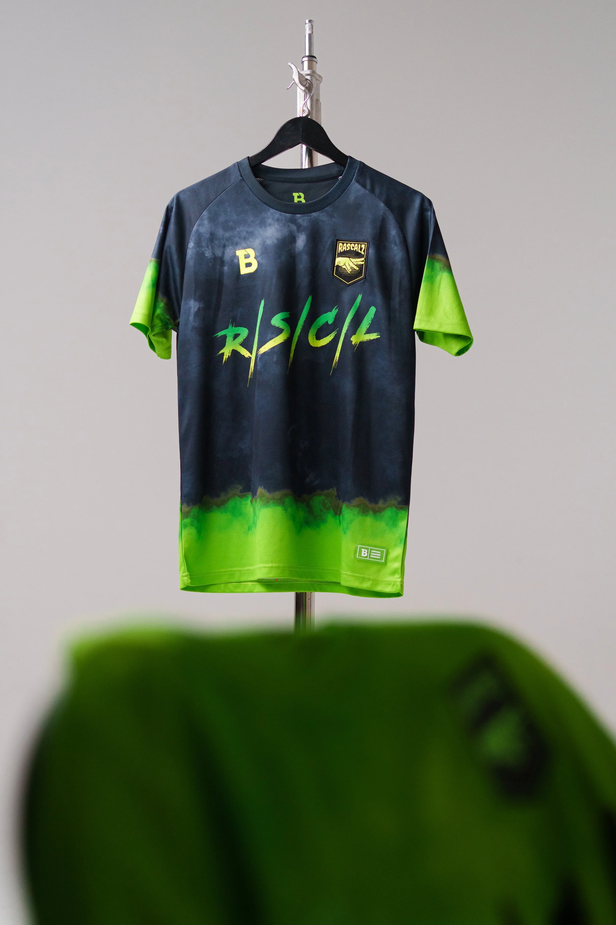 A black and green RASCALZ sports jersey hanging on a hanger with a plain background.