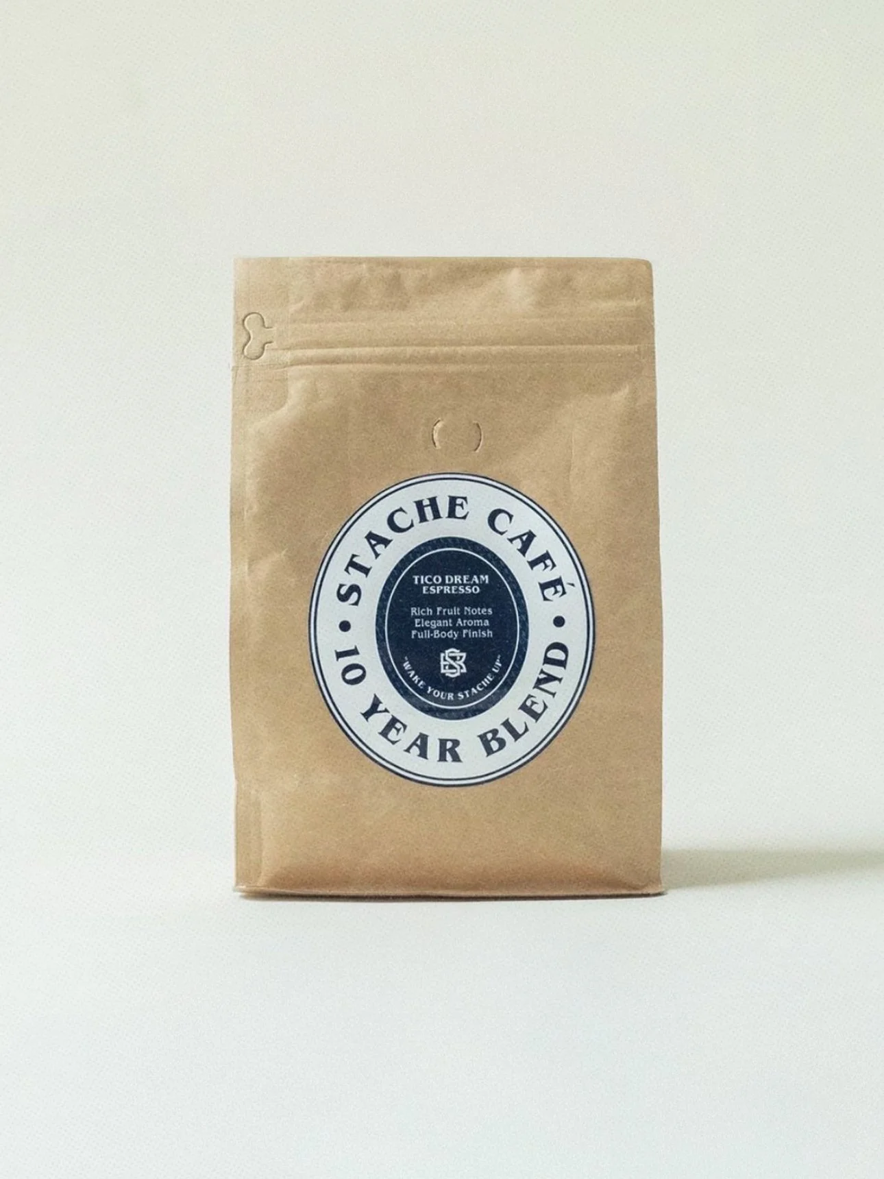 Brown paper bag of Stache Cafe 10 Year Blend coffee with a circular label on the front.