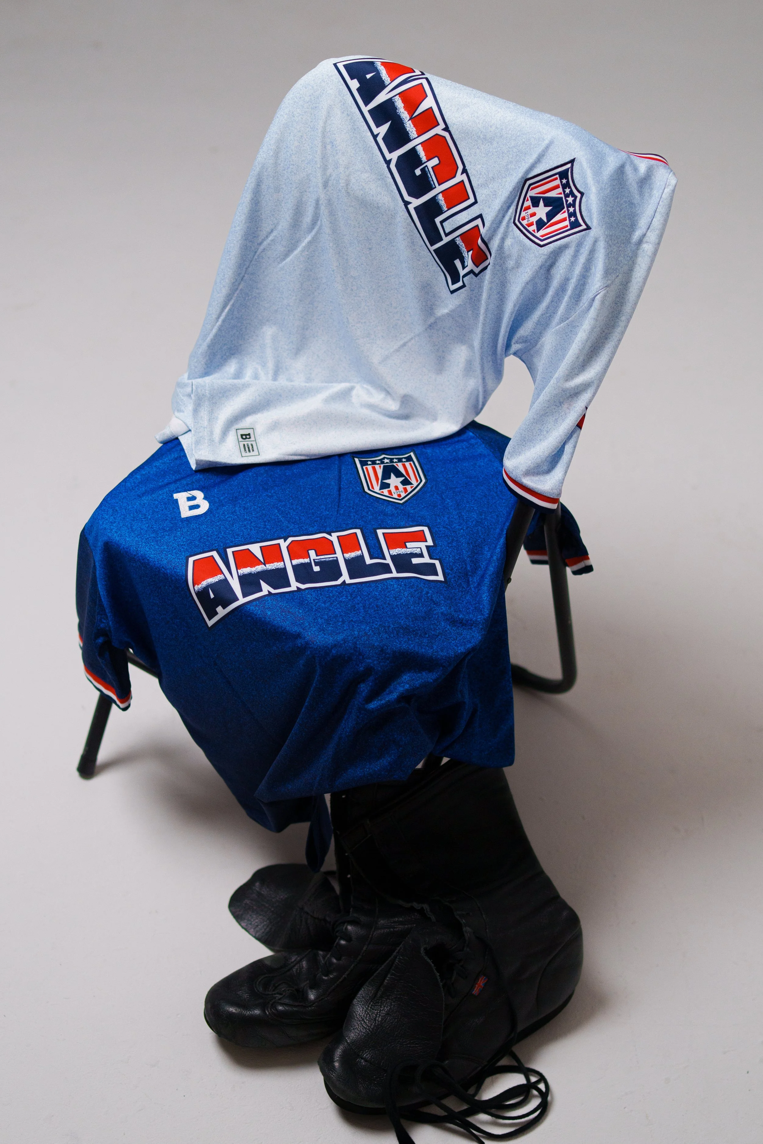 A hockey jersey, pair of hockey skates, and a black hockey glove arranged on a surface.