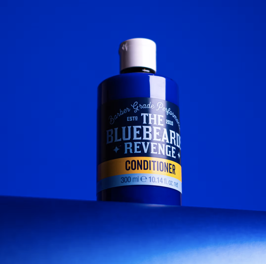 Blue bottle of The Bluebeard Revenge conditioner against a blue background.