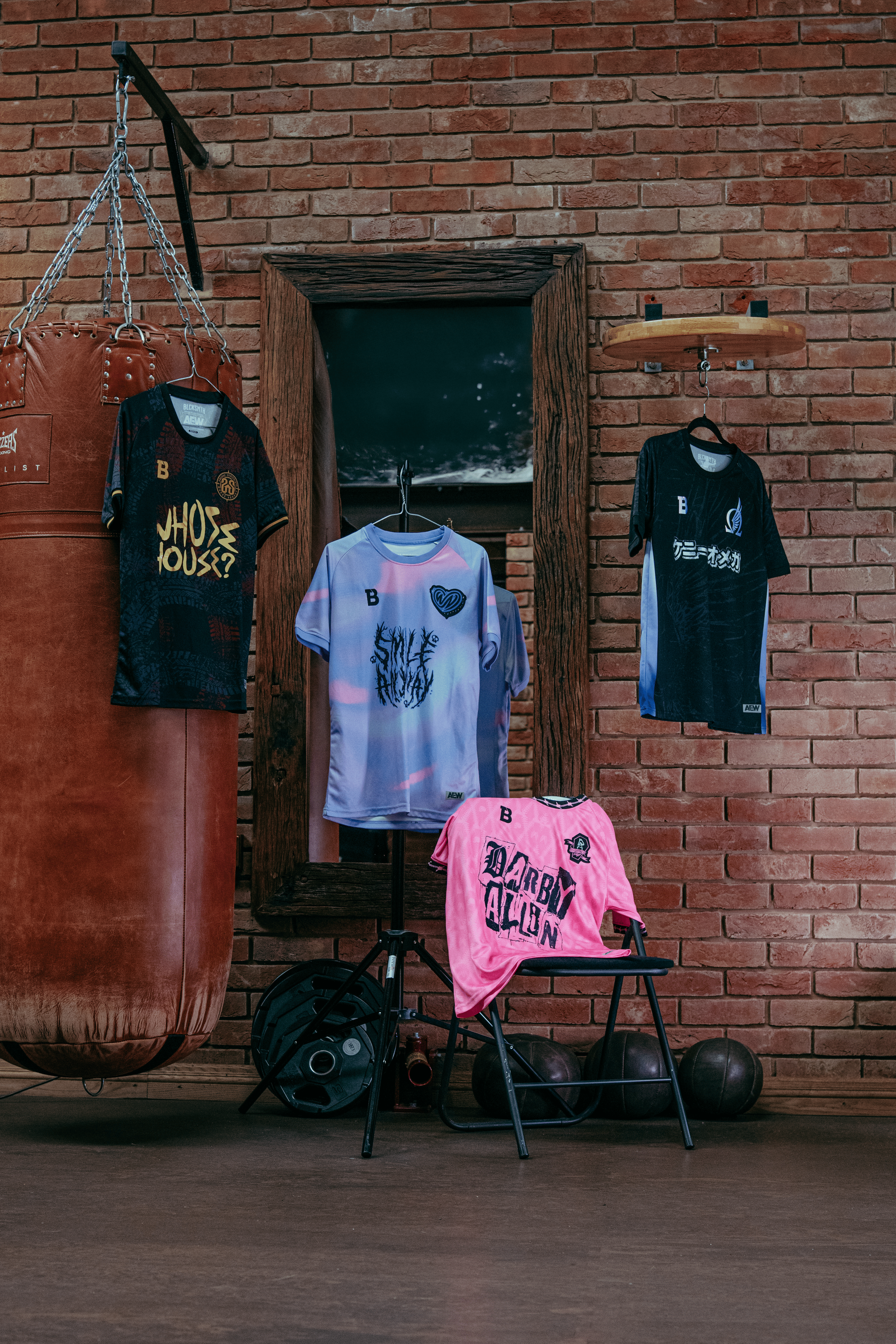 Collection of colorful soccer jerseys hanging on a gym wall, with a punching bag, gym equipment, and a brick wall background.