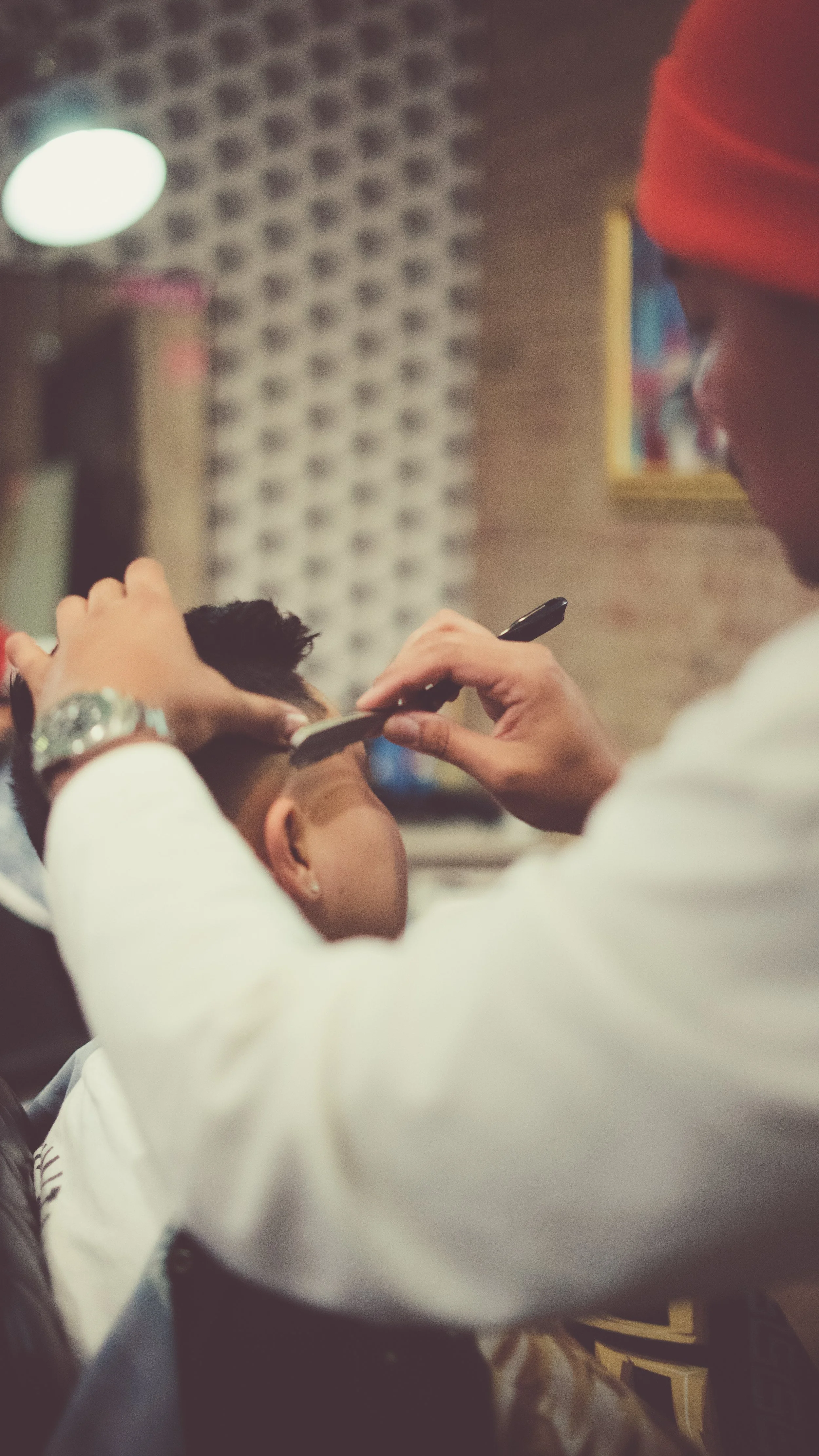 Barber cutting a customer's hair in a salon, with a focused barber using scissors and a comb.