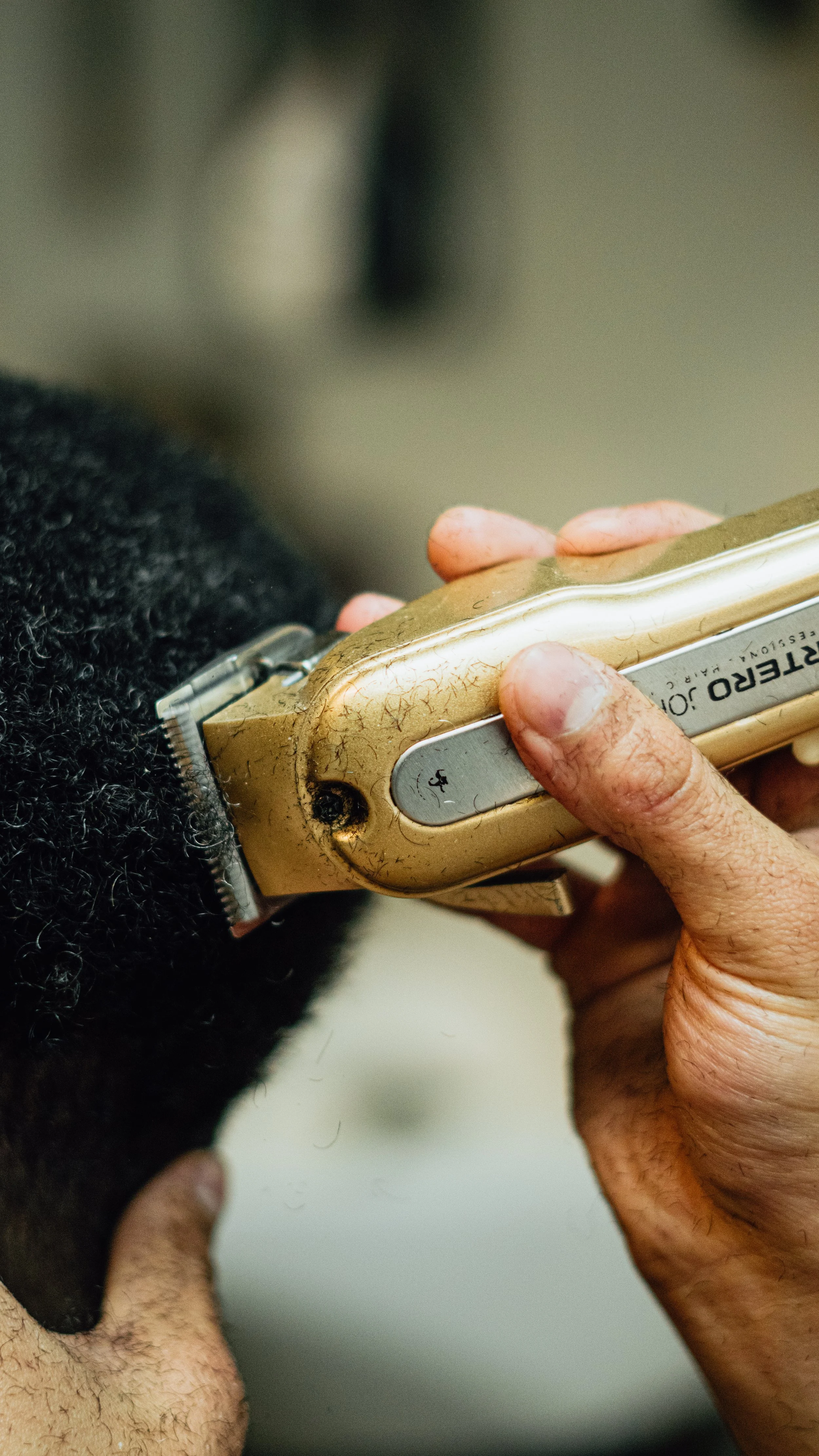 A person is using a vintage electric hair clipper to cut hair.