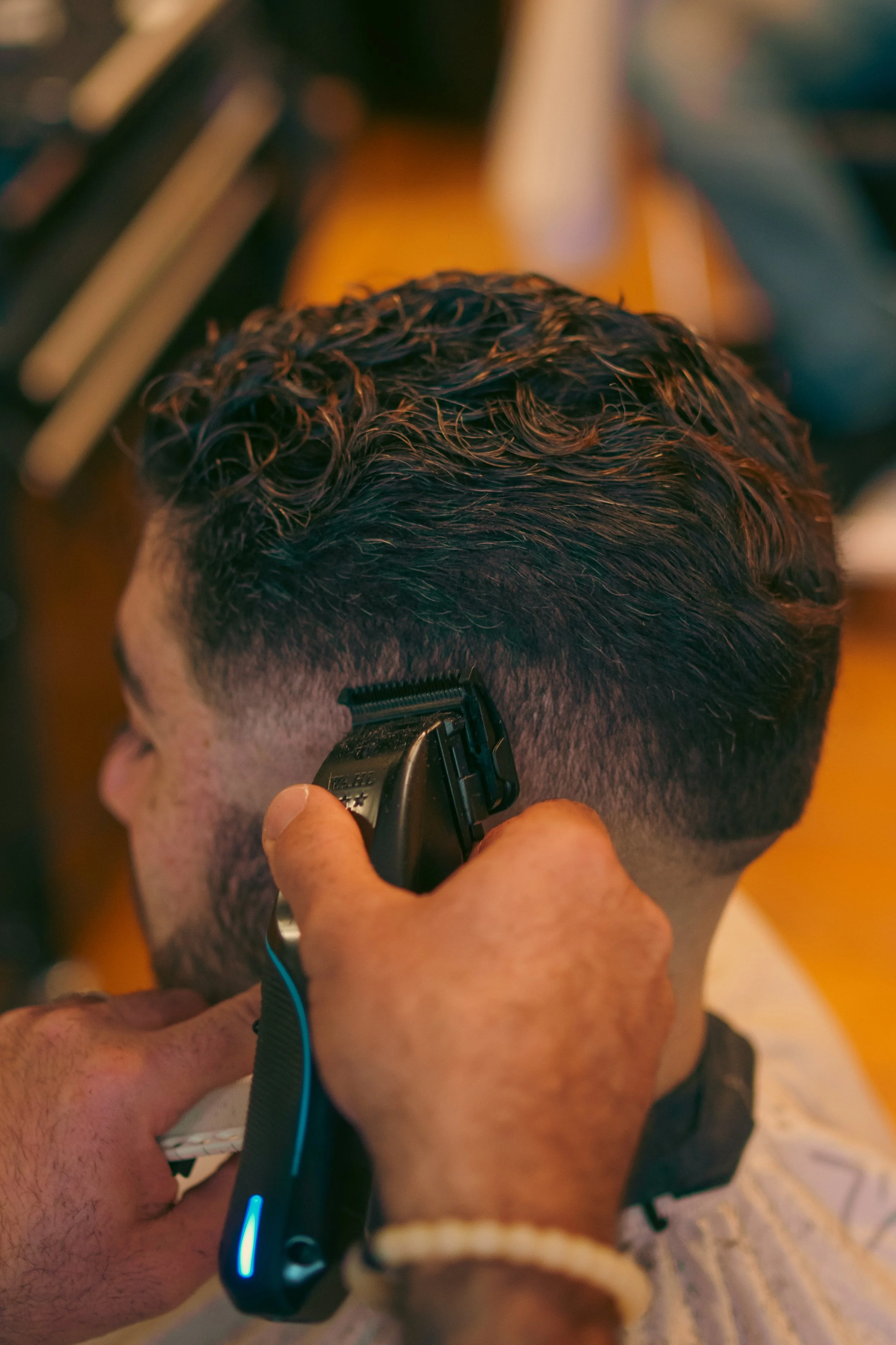 Close-up of a barber cutting a man's hair with a clippers in a barbershop.