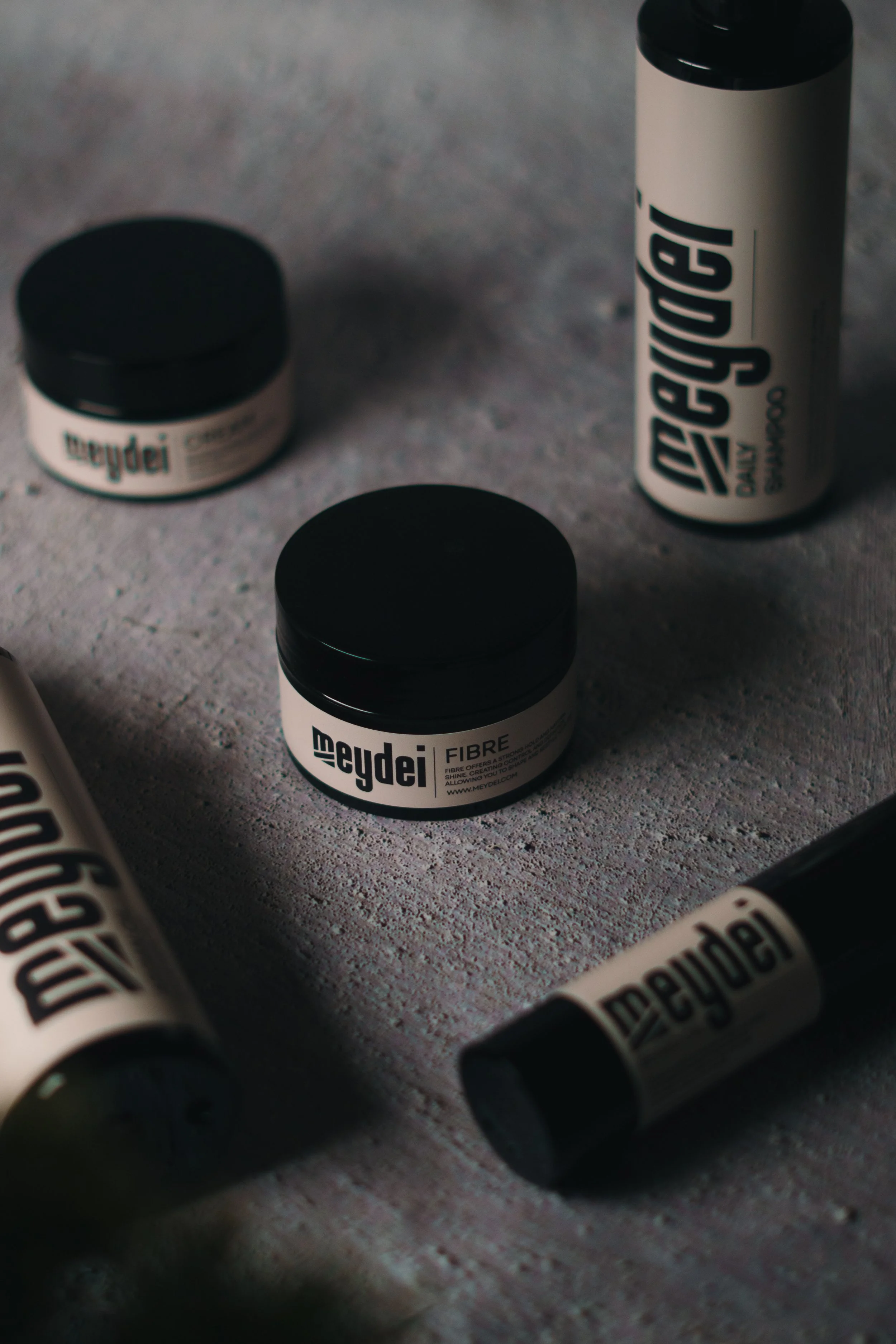 Several containers of Meydei brand products, including a small jar labeled 'Fibre' and tall bottles, are arranged on a textured surface.