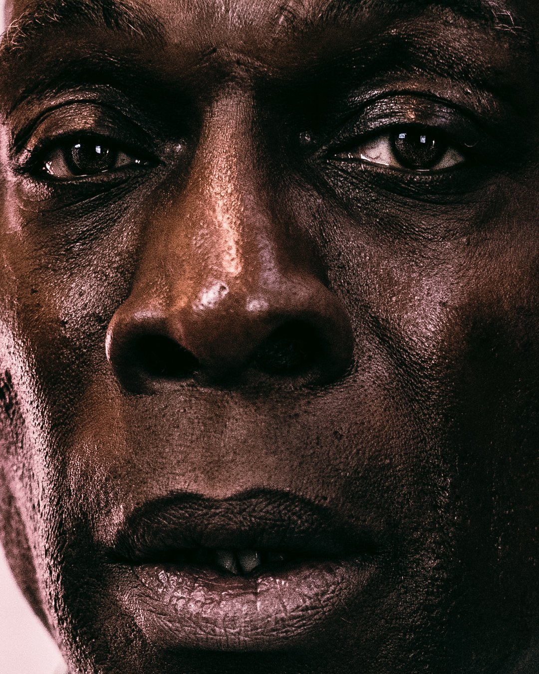 Close-up of a person's face with dark skin, showing detailed facial features including eyes, nose, and lips.