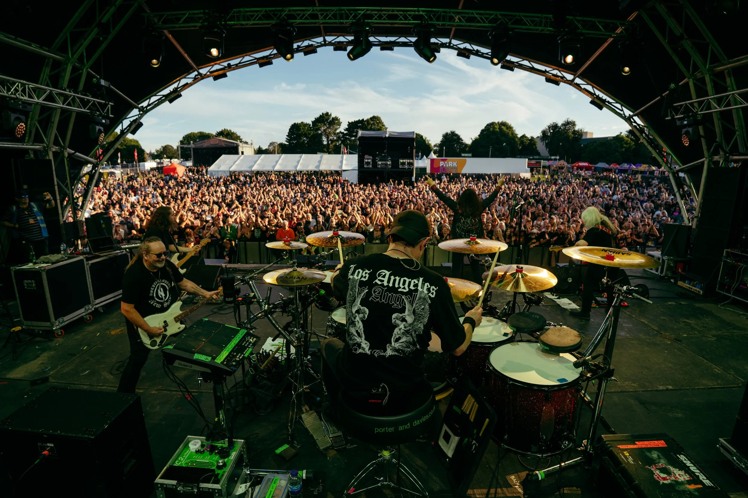 Band performing on stage at an outdoor music festival with a large audience.