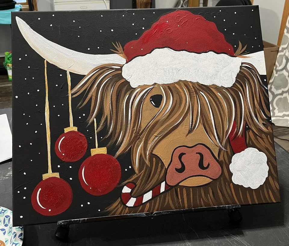 Painted canvas of a Highland cow wearing a Santa hat with Christmas ornaments hanging from its horns.