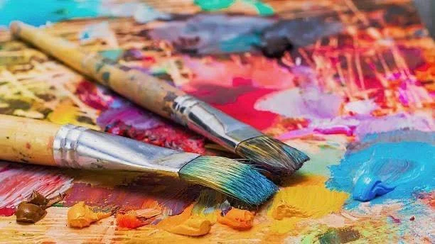 Two paintbrushes resting on an artist's palette covered with colorful paints.