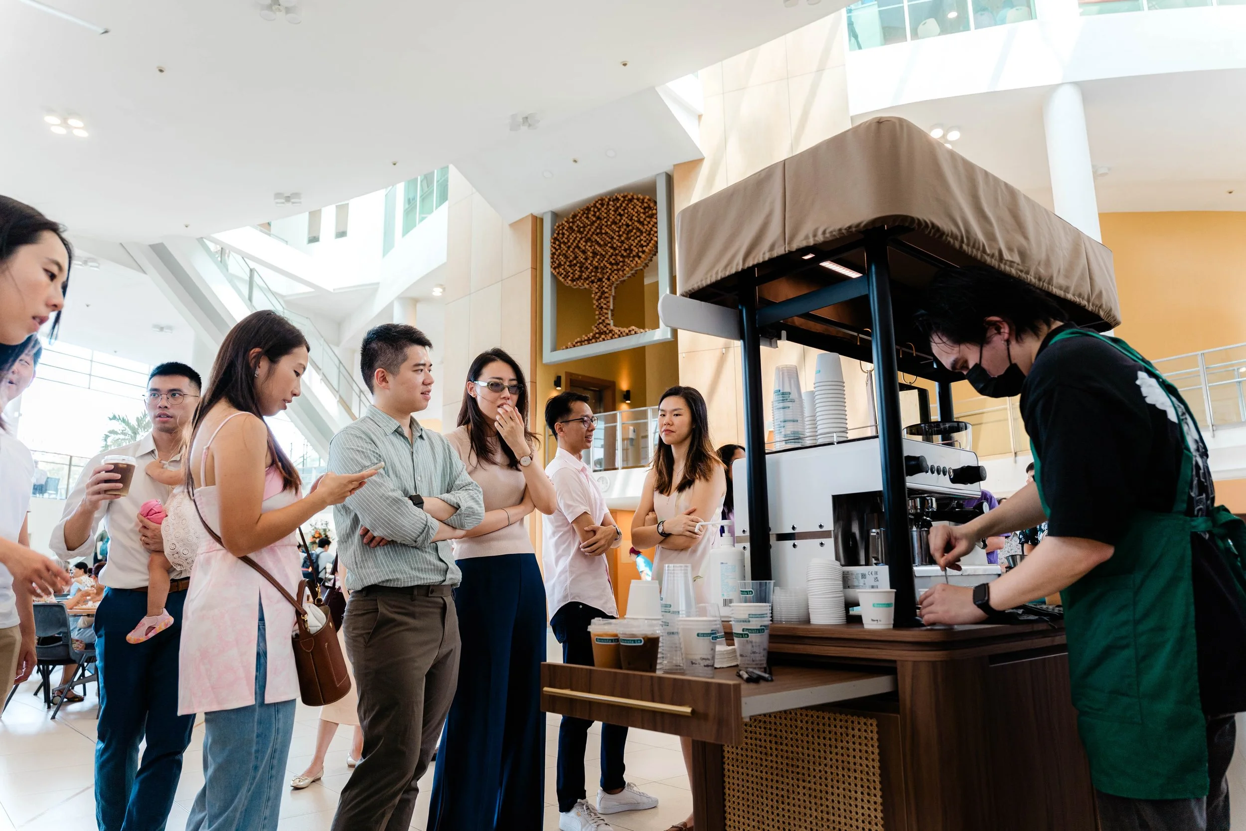 People standing in line at a coffee stand in a modern shopping mall.