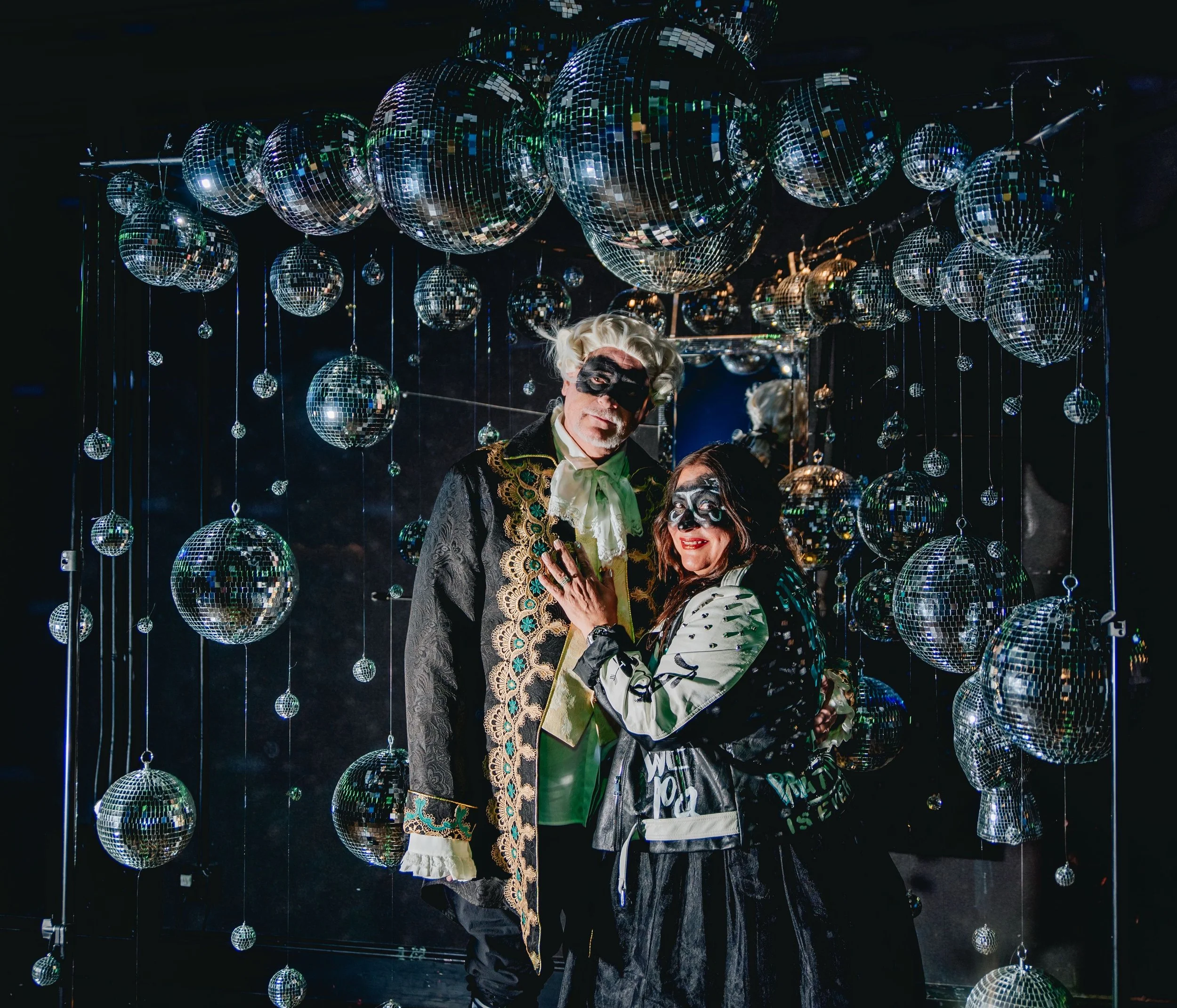 People dressed as pirates in front of a wall of disco balls at a party or celebration.