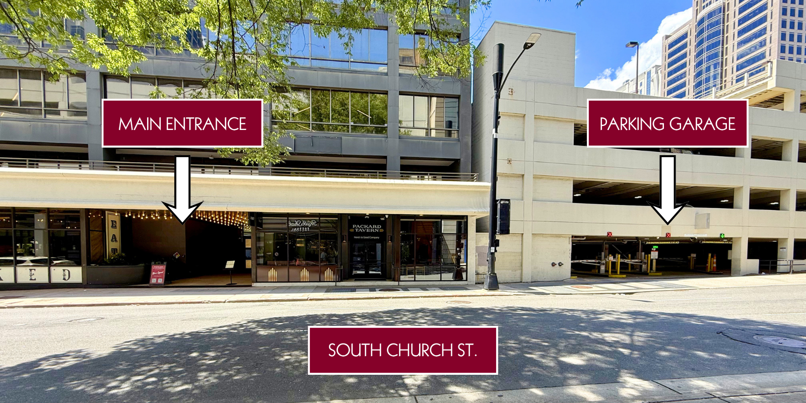 A street view of a building showing a main entrance to a restaurant or cafe on the ground floor and a parking garage to the right, with signs pointing to each entrance. The building is on South Church Street, with trees and other high-rise buildings visible in the background.