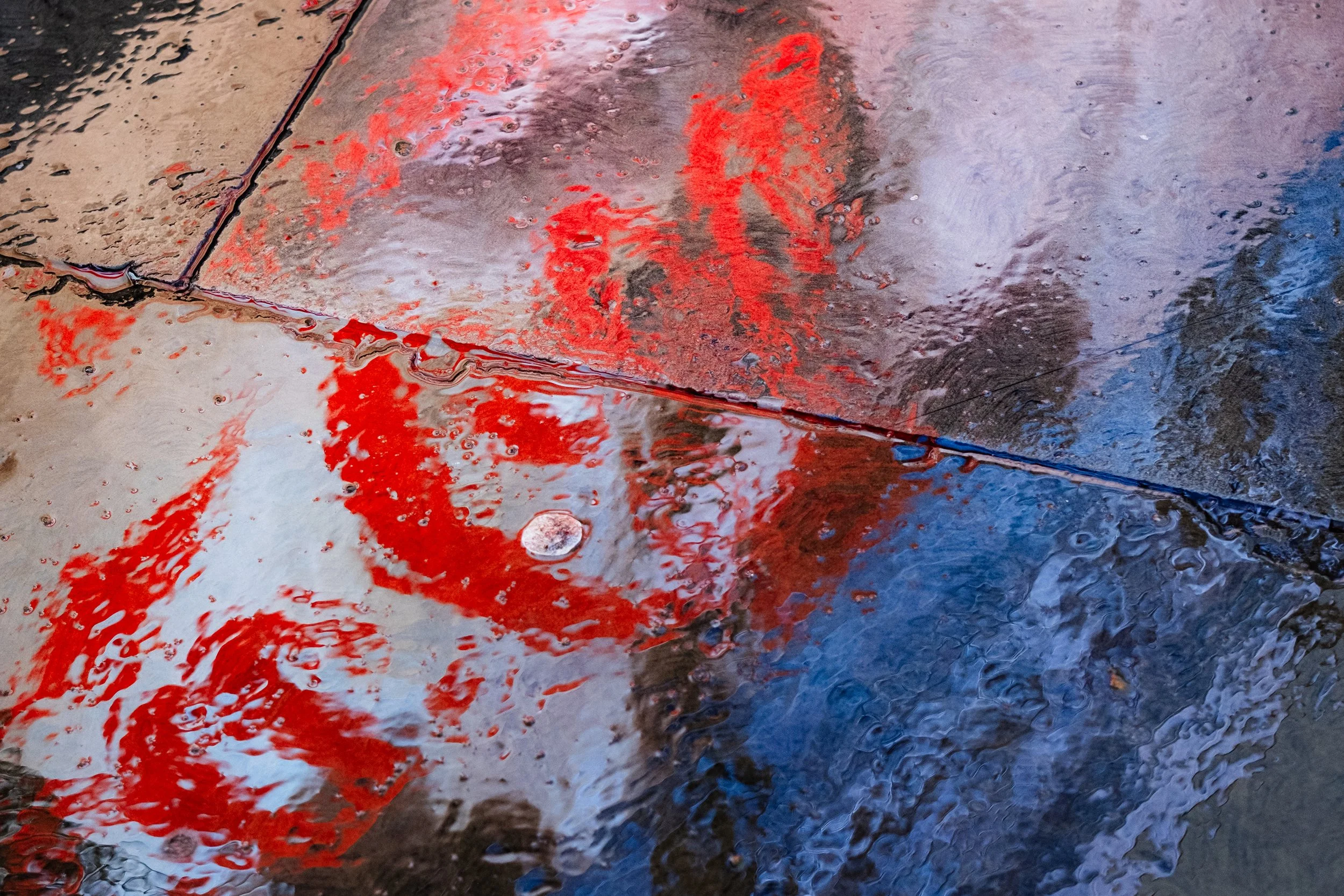 Reflection of Coca Cola billboard on wet pavement. 