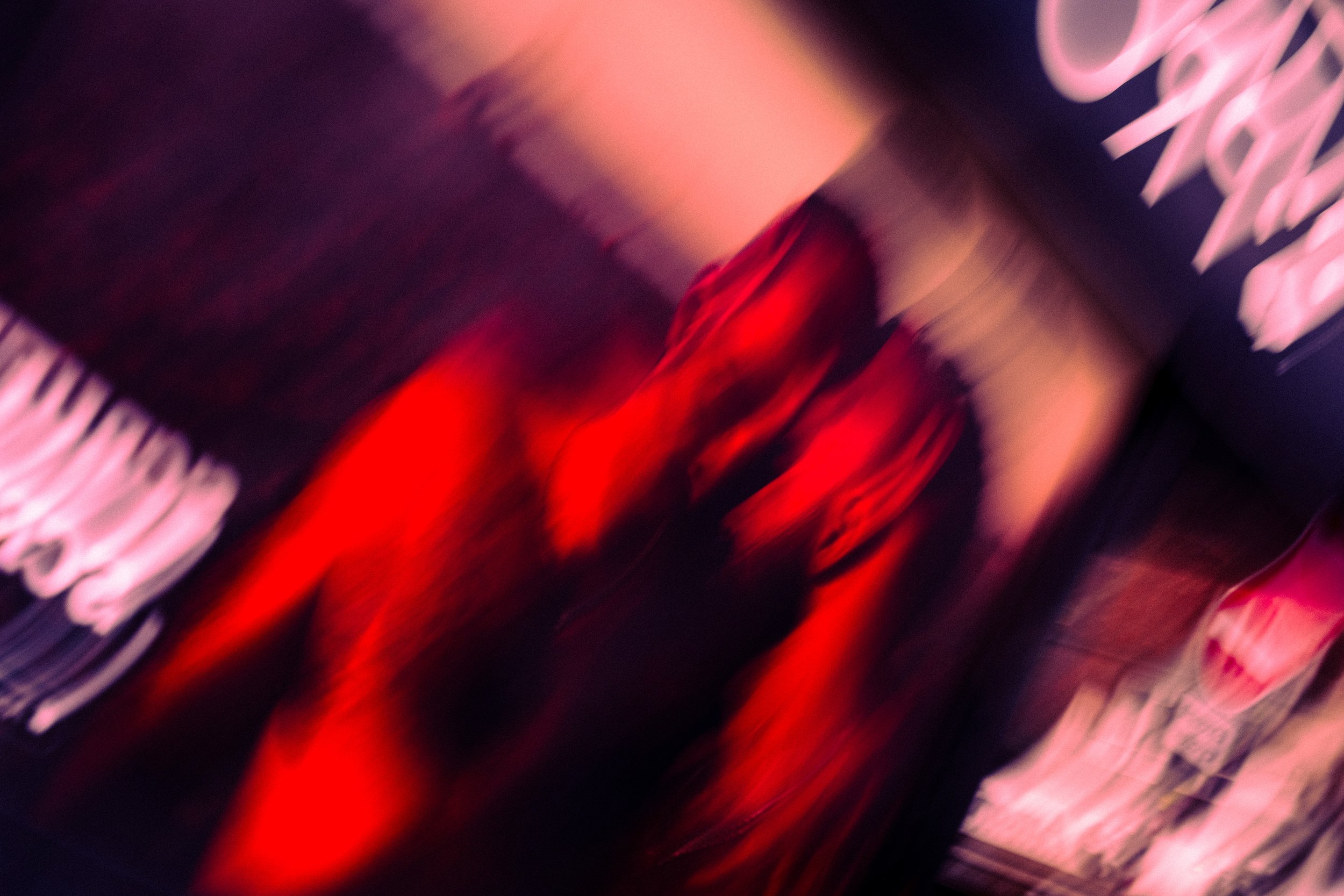 A blurred image in red and black colours showing two mean standing next to each other.