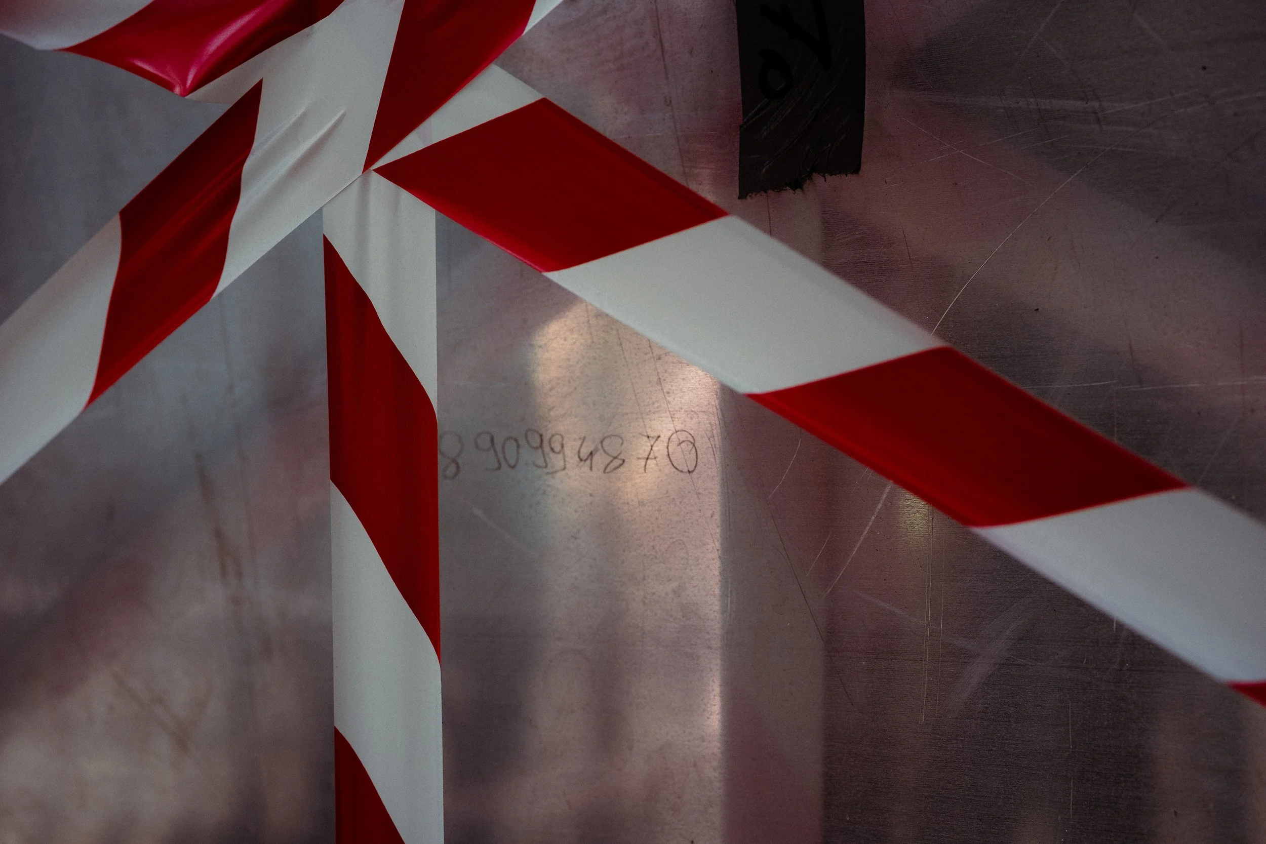 A red and white striped caution tape on a metal surface.