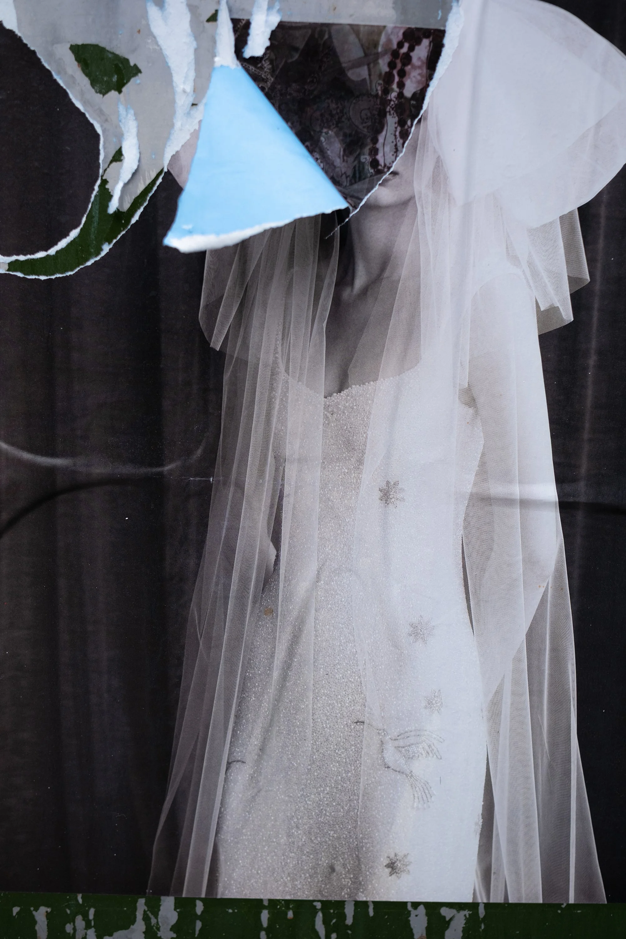 A ripped poster of wedding dress made of glittery white fabric with snowflake embellishments, flowing behind a bride with sheer tulle fabric on her shoulders.
