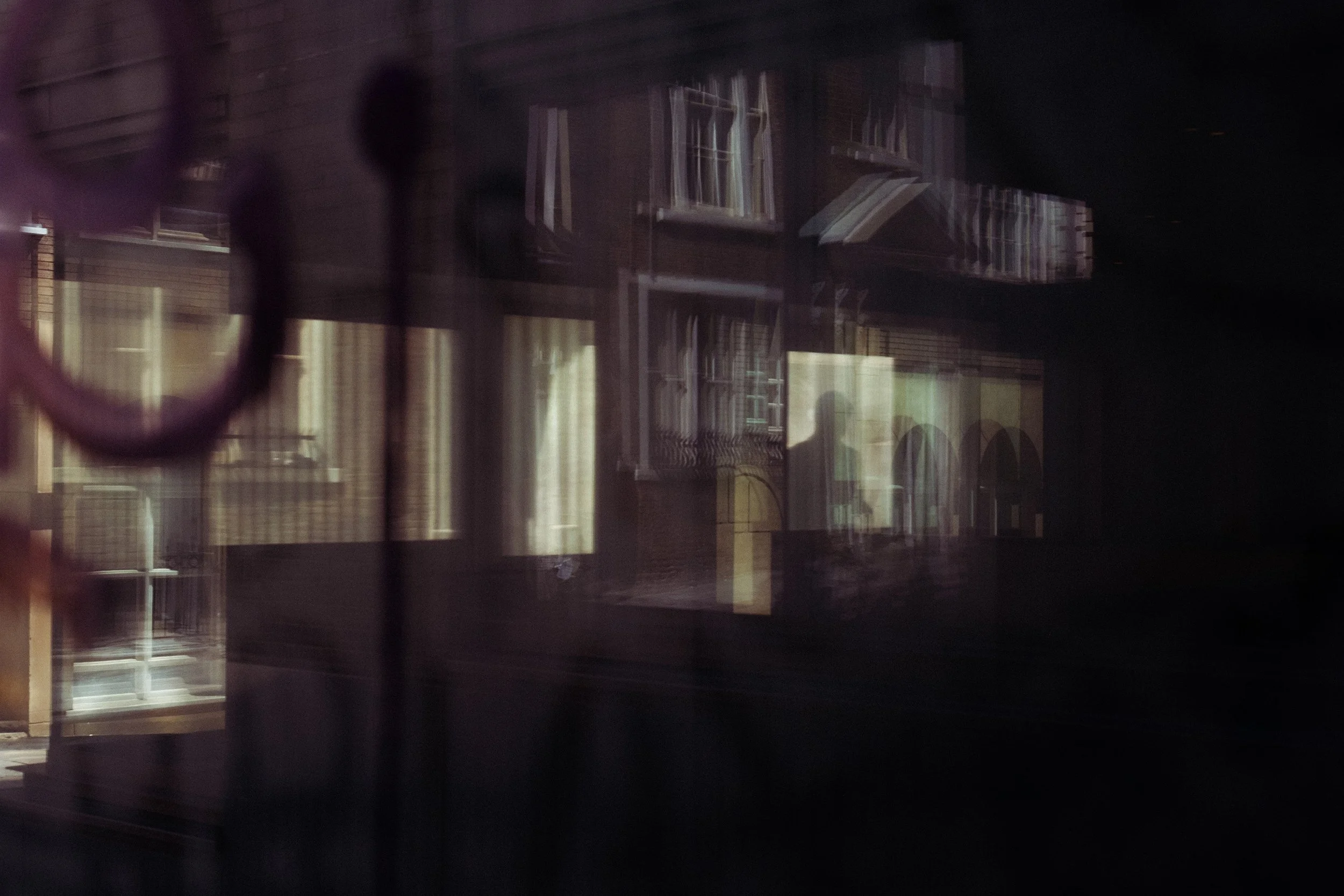 Reflection of a person walking down a road and exterior relfecting in a glass window.