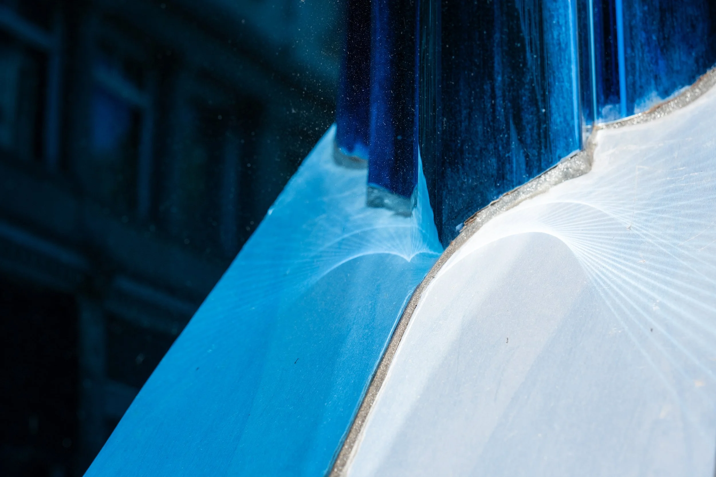Close-up of a blue and white glass with a textured surface and a small patch of a crystal-shaped reflection.