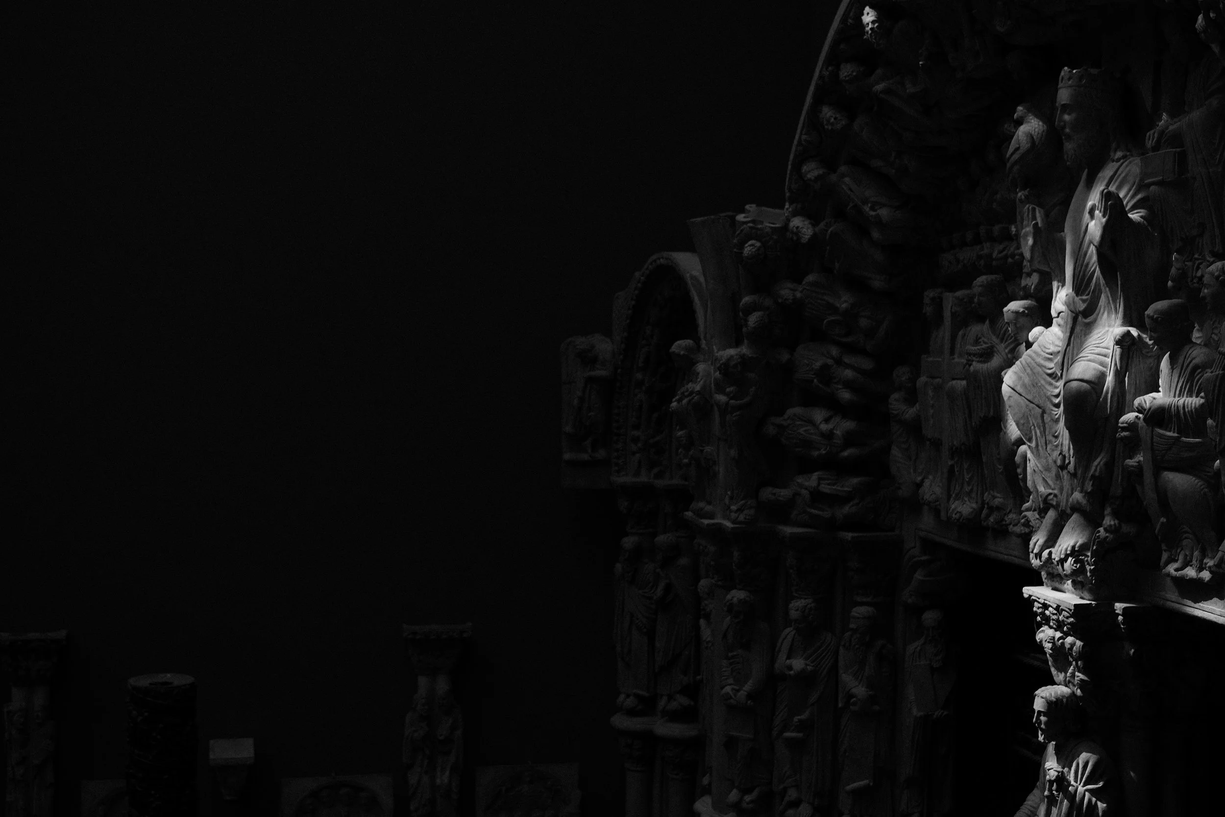 Black and white photo of intricately carved stone sculptures depicting figures.