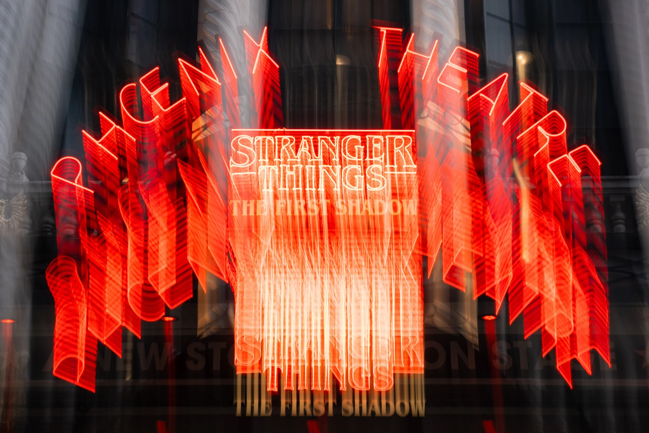 Neon sign of the title "Stranger Things" with the subtitle "The First Shadow" displayed with a blurred background.