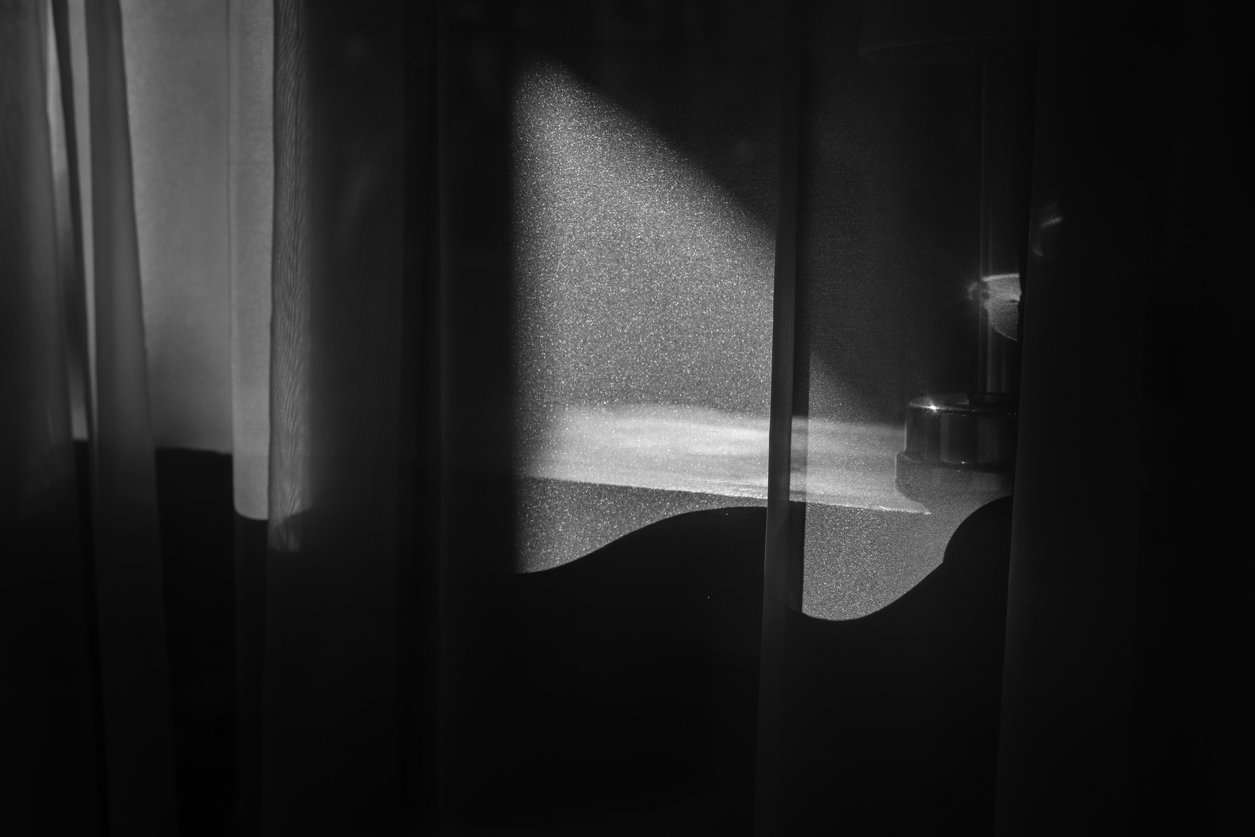 A black and white photo of a speaker cone inside an electronic device, with light reflecting off its surface.