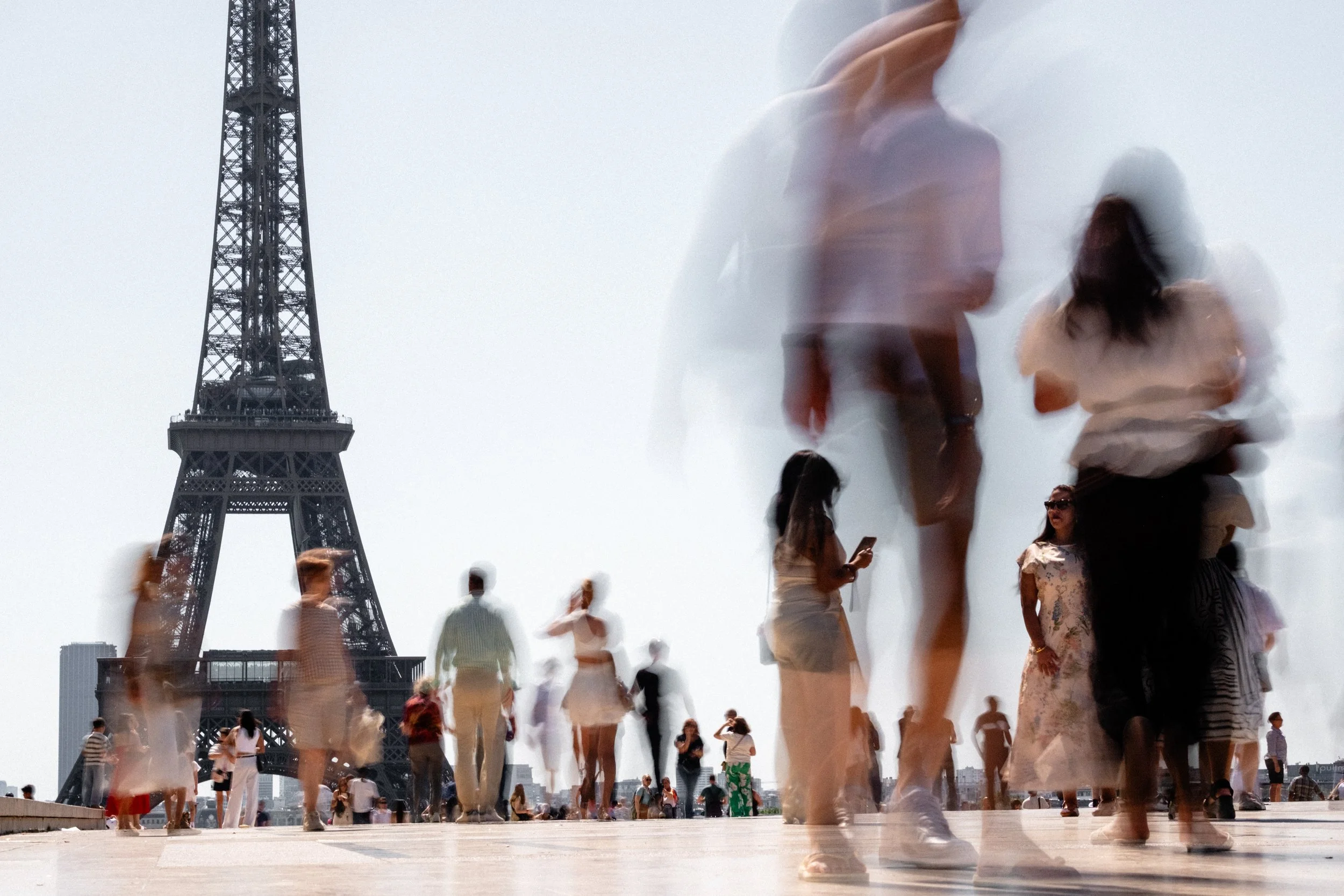 People partly in motion blur standing in front of the Eiffel Tower at the Place du Trocadéro