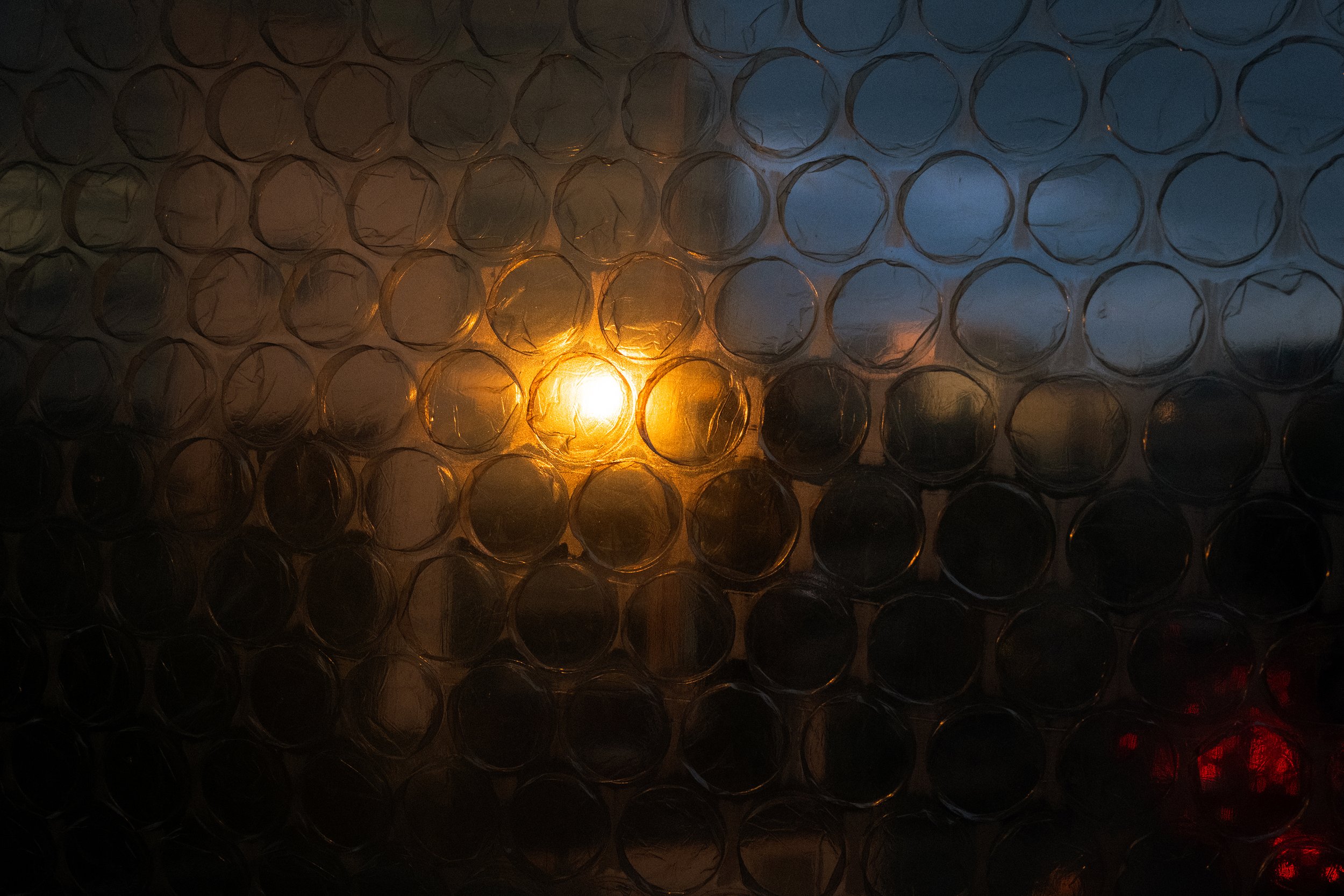 Blurry cityscape seen through bubble wrap with evening sun reflecting in the window of a high-rise office building. 