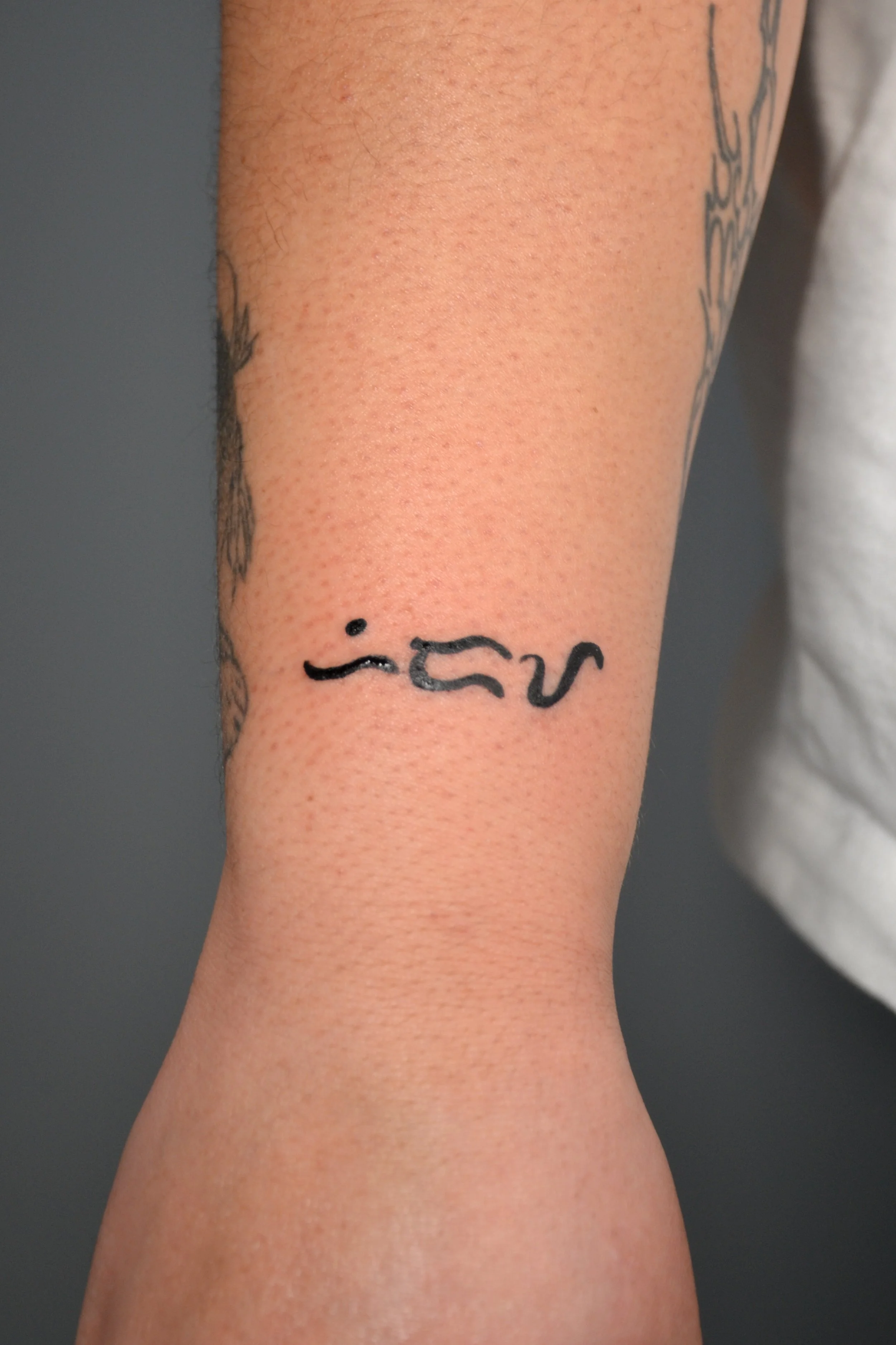 Picture of a woman's arm/wrist with the tattoo baybayin text meaning hiraya (fruit of one's hopes and dreams).