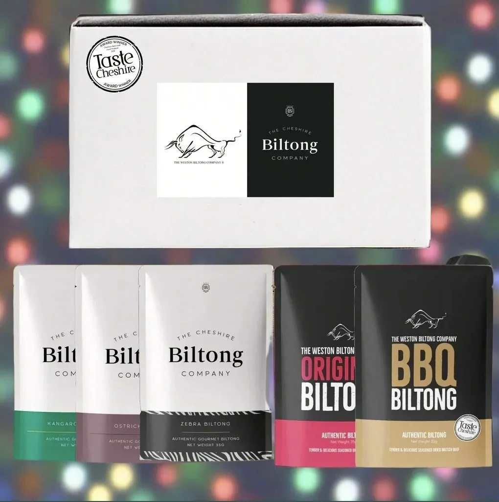 Various packages of Biltong from The Cheshire Biltong Company, including Kangaroo, Ostrich, Zebra, Original, and BBQ flavors, displayed with a cardboard box in the background.