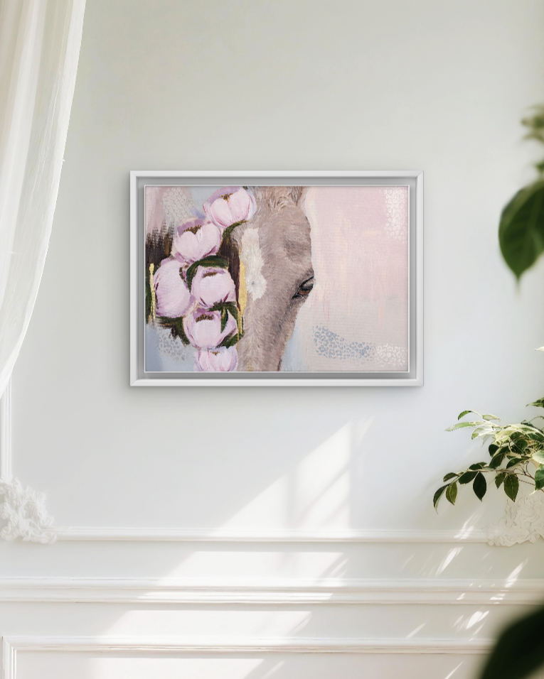 A framed painting of a horse's head with pink flowers next to it, hanging on a white wall with sunlight streaming through a window on the right.