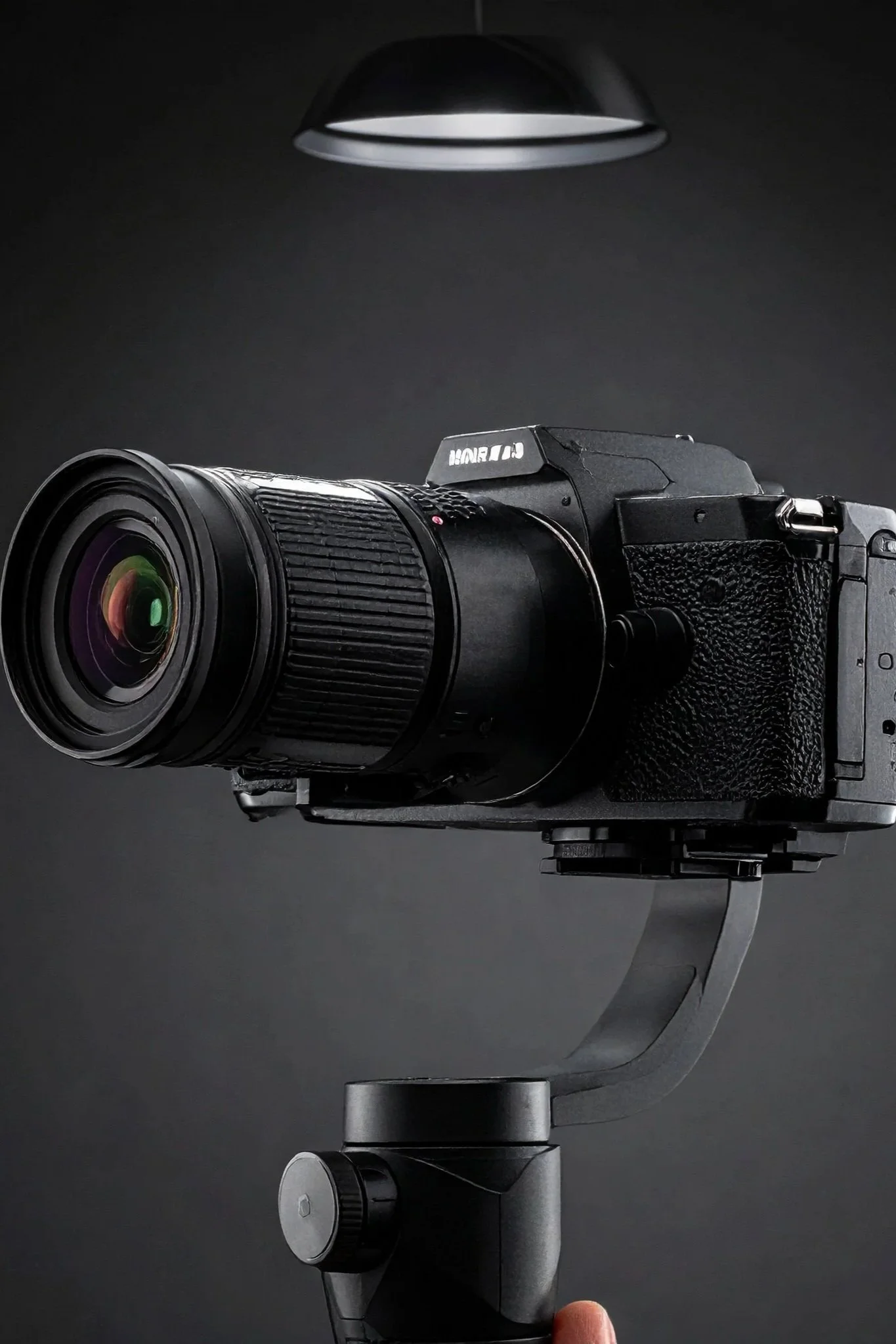 A black digital camera mounted on a gimbal stabilizer, with a close-up view of the camera lens, against a dark background.