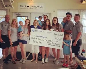 Group of people celebrating at a Four Diamonds charity event, holding a large check for $35,810 for children's cancer support, June 2018.