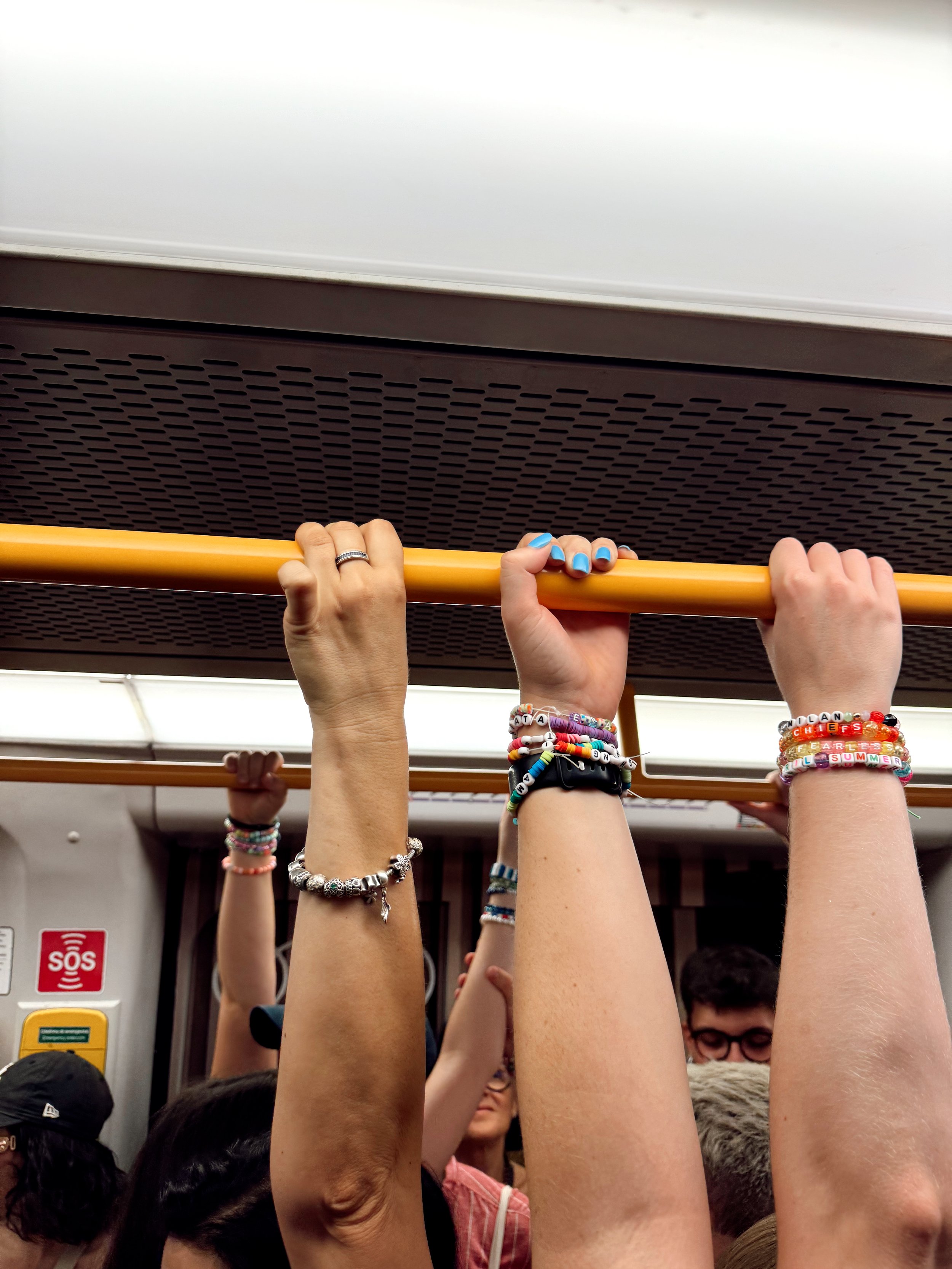 People holding onto yellow overhead railings inside a subway train.