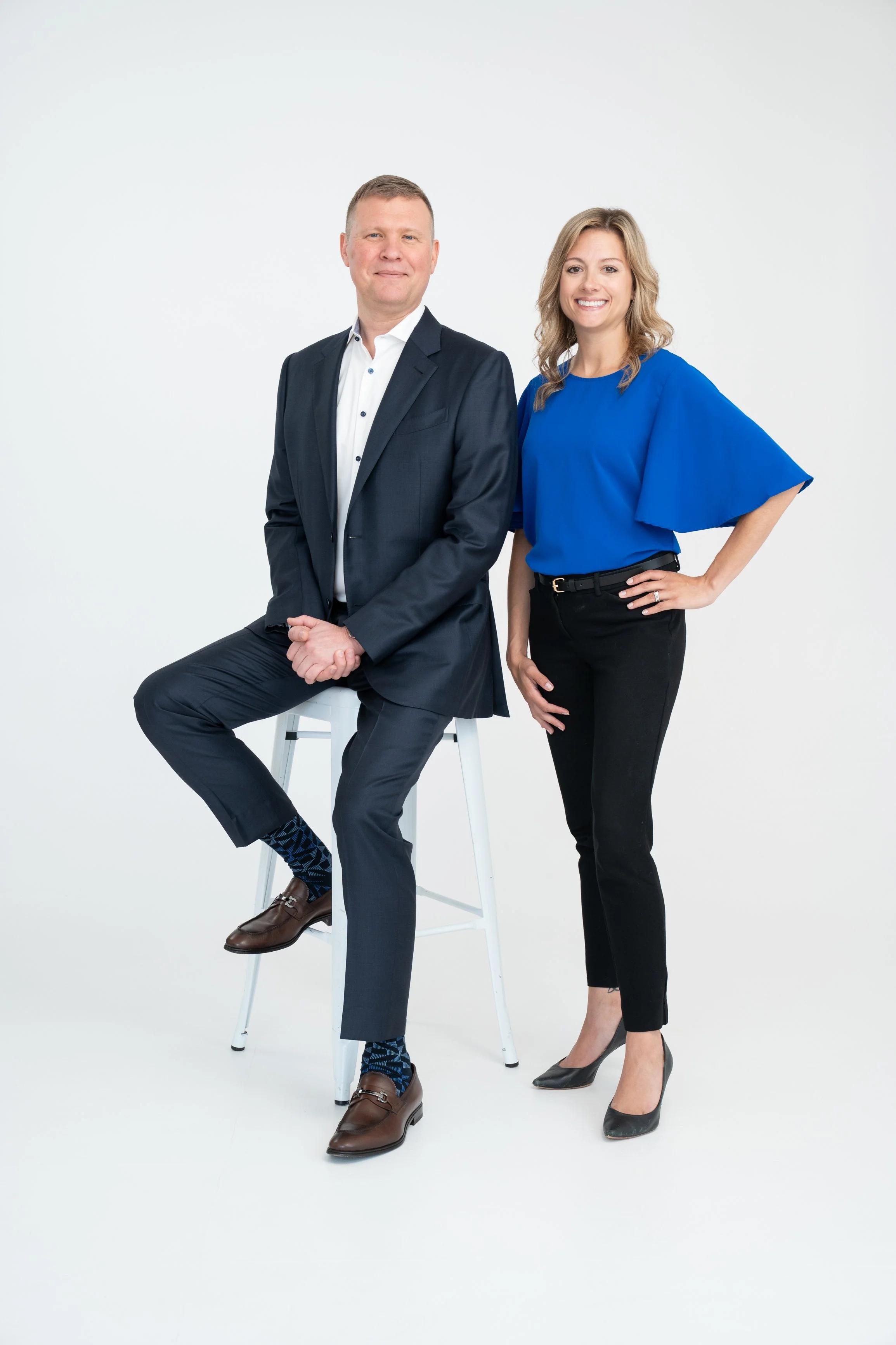 Man and woman in professional attire posing in front of a white background Detroit Marketing Agency
