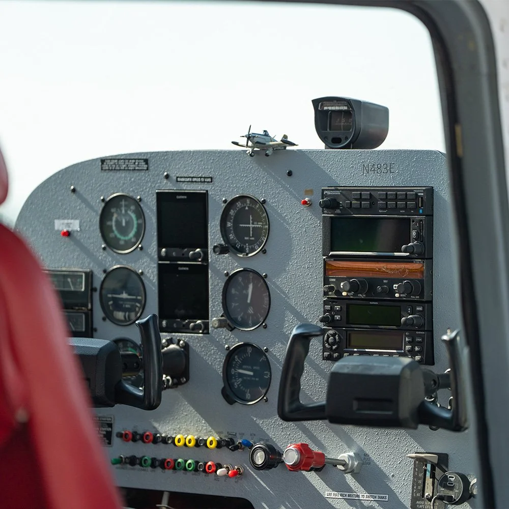 Interior cockpit of an aircraft with various gauges, dials, and instruments, a small toy airplane on top of the dashboard, and a radar device mounted at the top right.