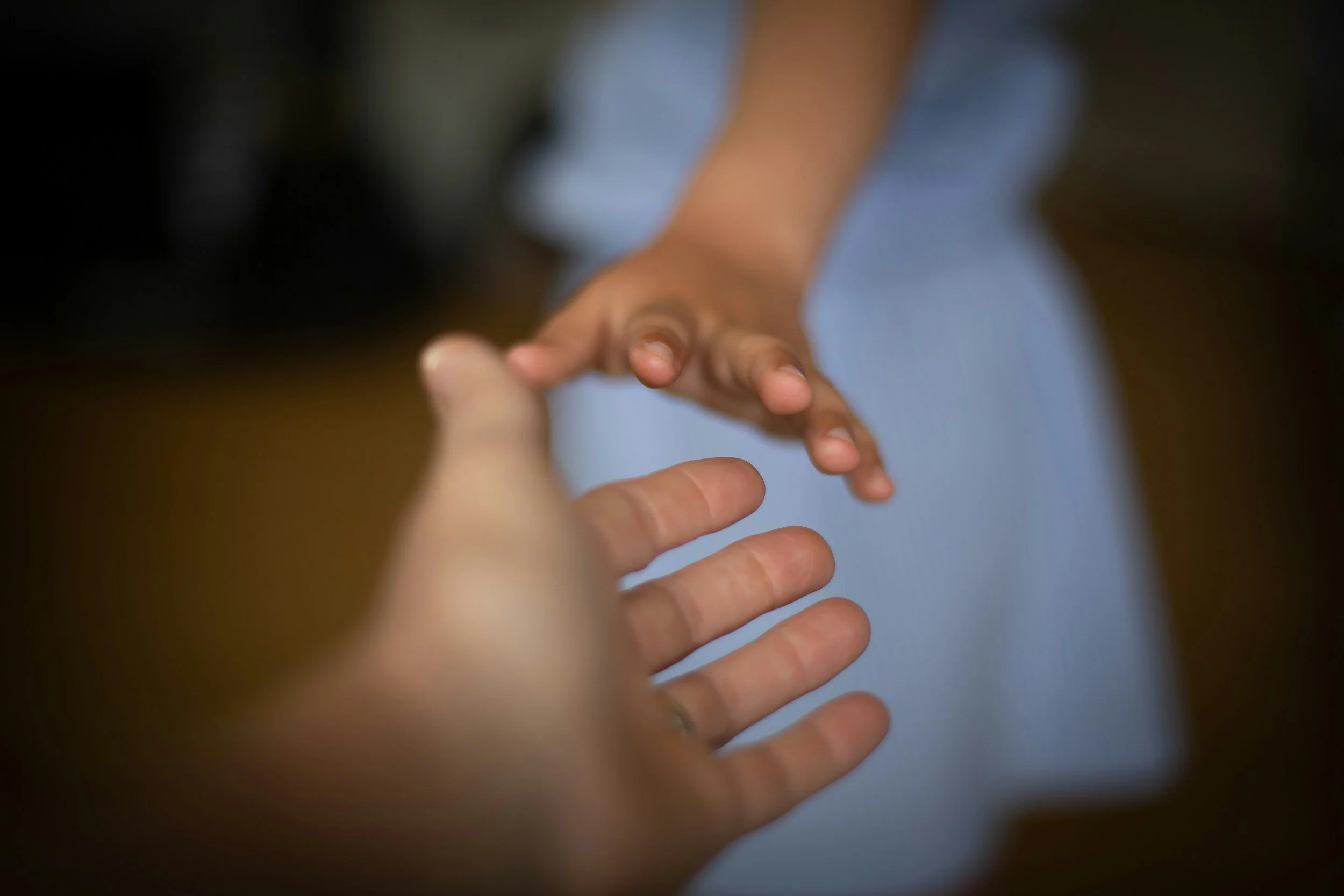 Two hands reaching toward each other, symbolizing care, connection, and human support.