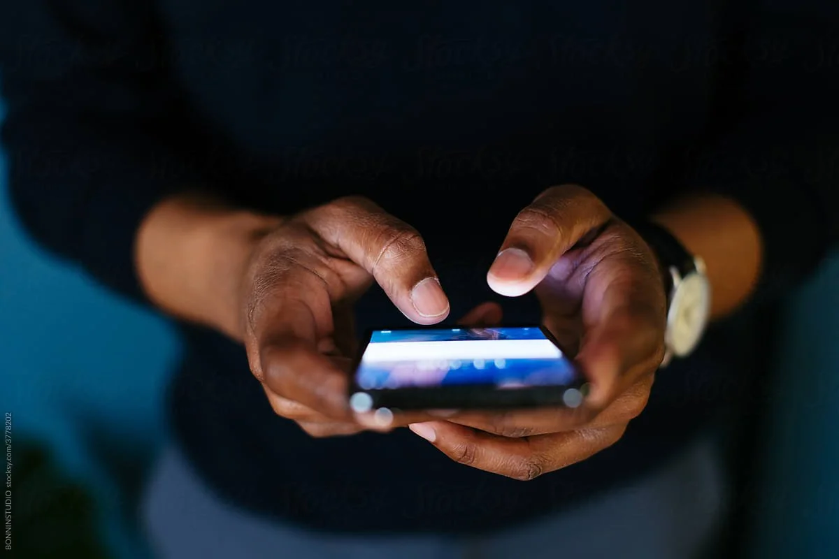 Person using a smartphone, holding it with both hands, fingers on the screen.