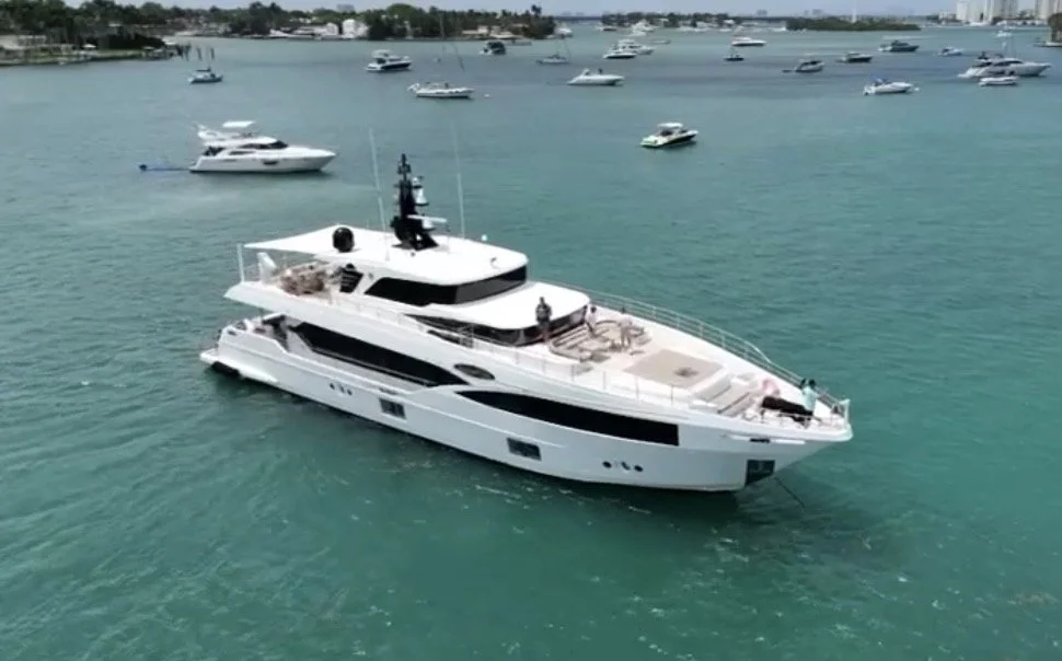 Large white yacht with multiple decks floating on turquoise water, surrounded by various smaller boats and boats in the background.