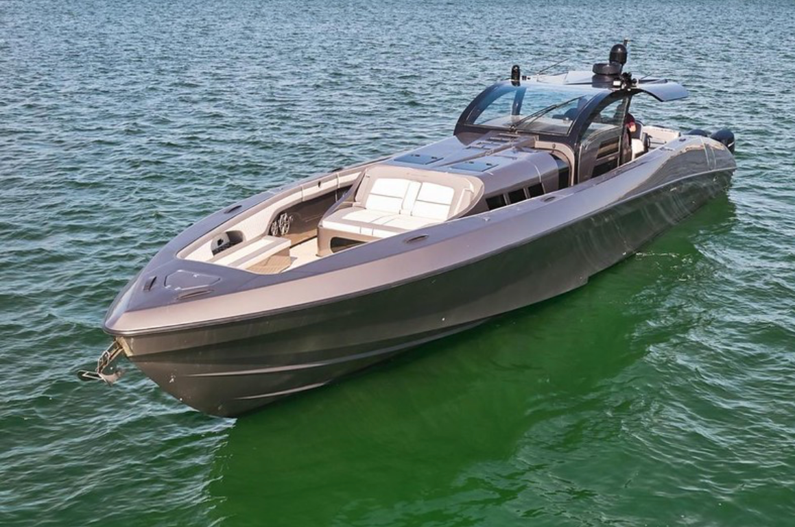 A sleek, modern motorboat on calm water, with a glass-enclosed cabin and white seating area.