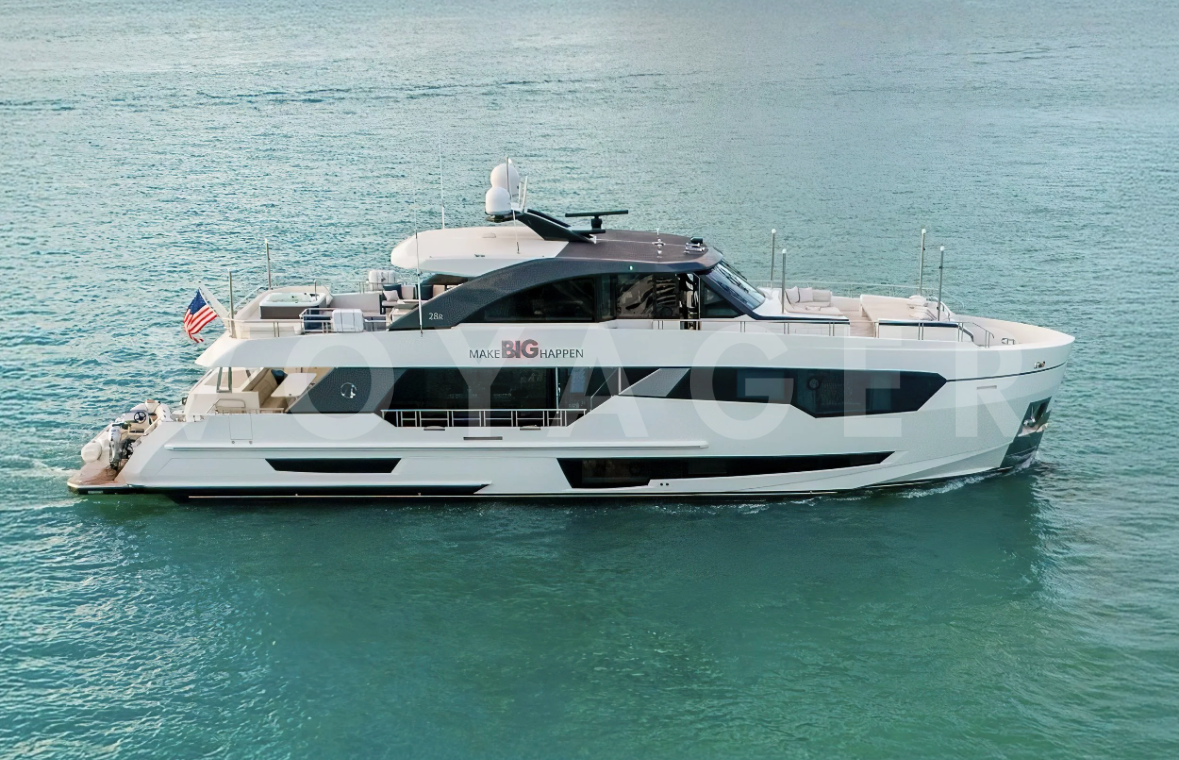 A large white yacht sailing on calm ocean waters with an American flag on the stern and a sunshade on the deck.