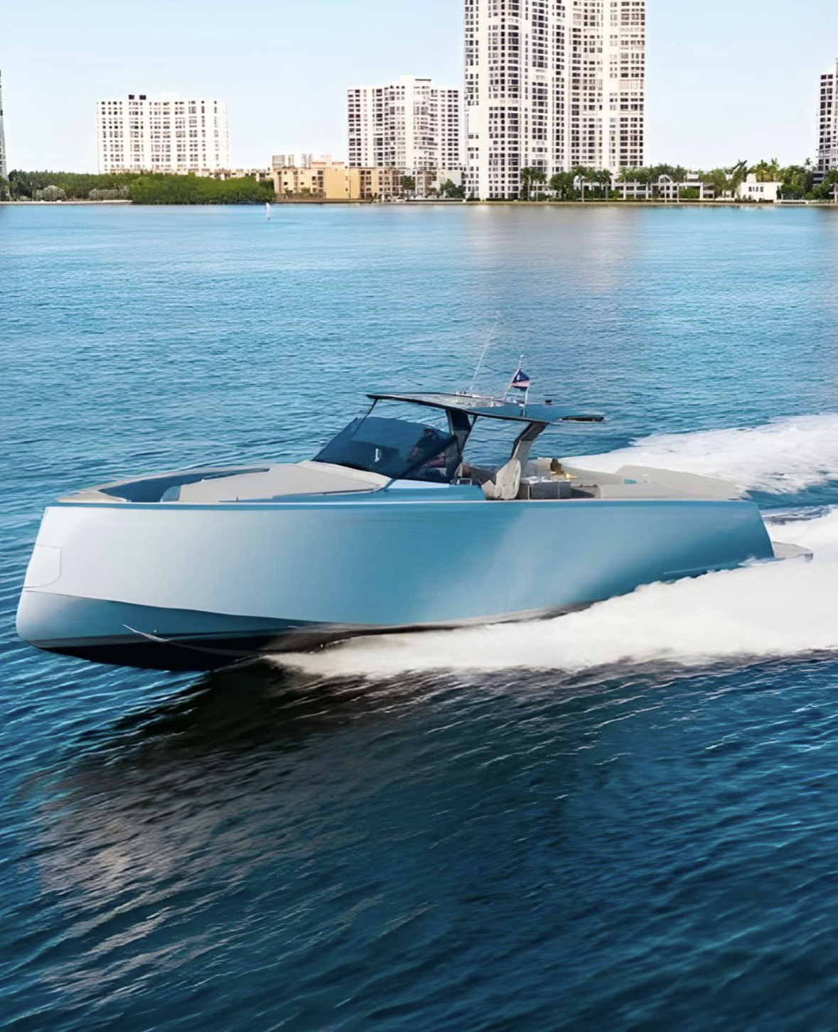 A modern yacht speeding through turquoise water with a city skyline and tall buildings in the background.