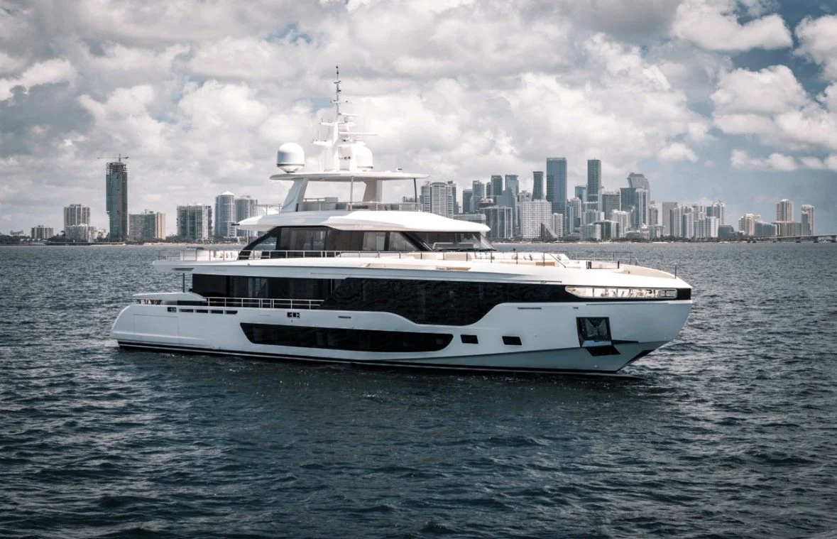 A luxury yacht sailing in the water with a city skyline in the background.