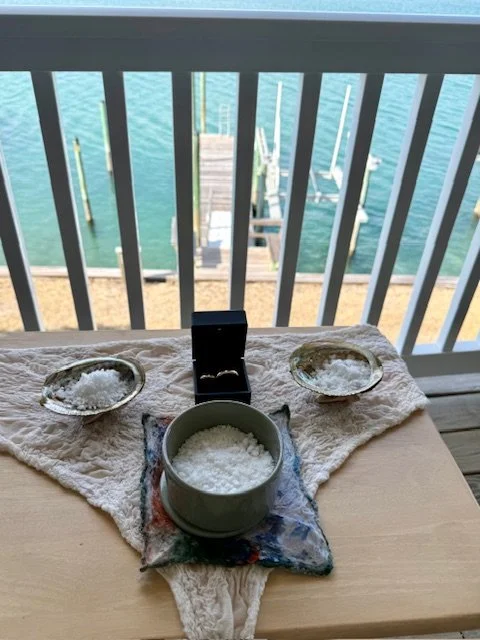 Breakfast setup on a table by a balcony overlooking the water with boats docked at a pier.