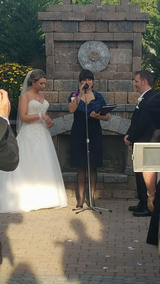 wedding officiant with bride and groom at microphone