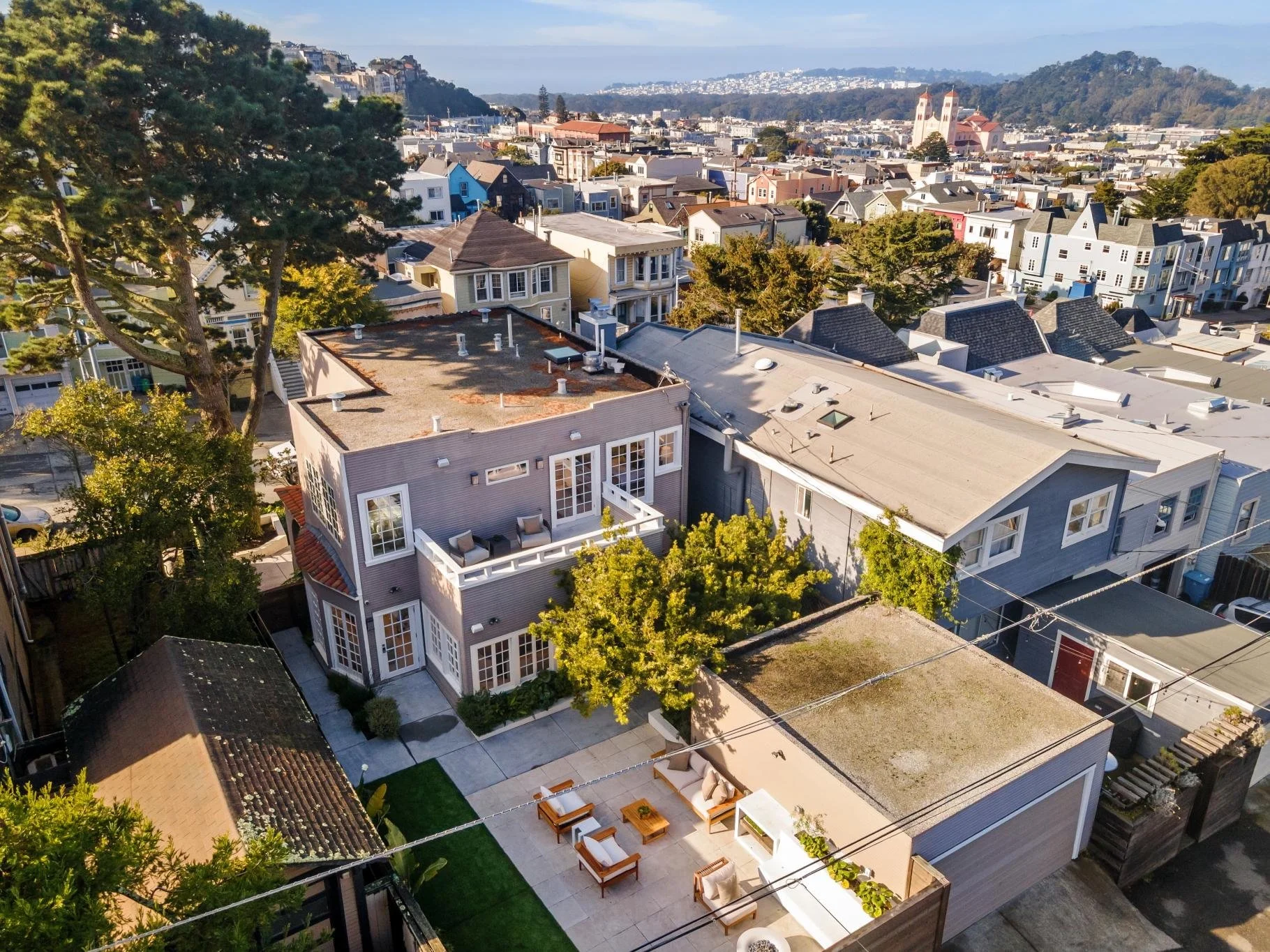 Aerial view of a neighborhood with houses, trees, and a hill in the background.