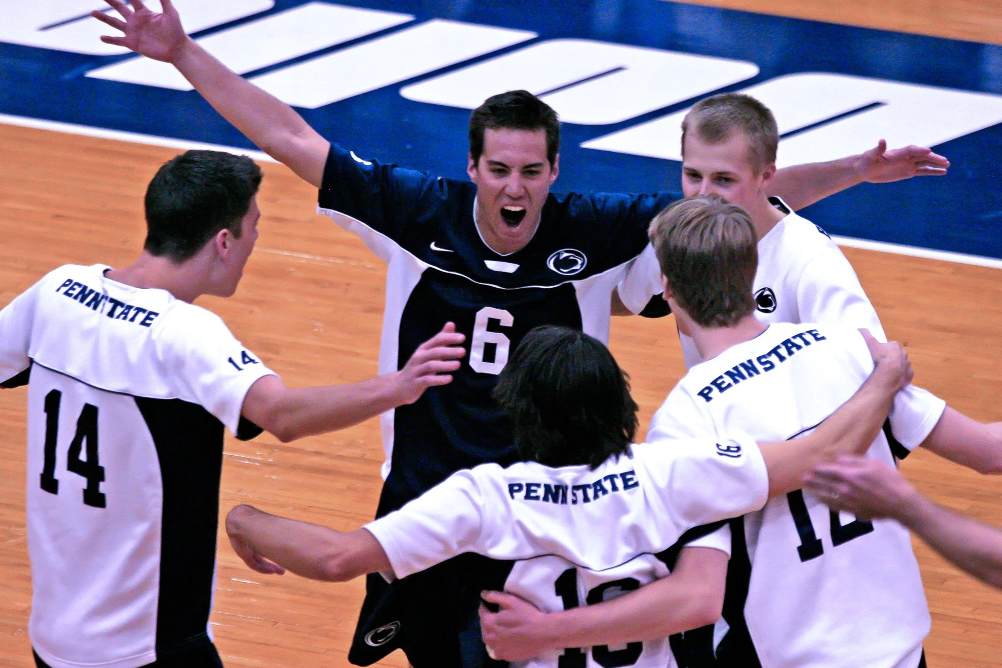 Penn State volleyball team celebrating on the court.