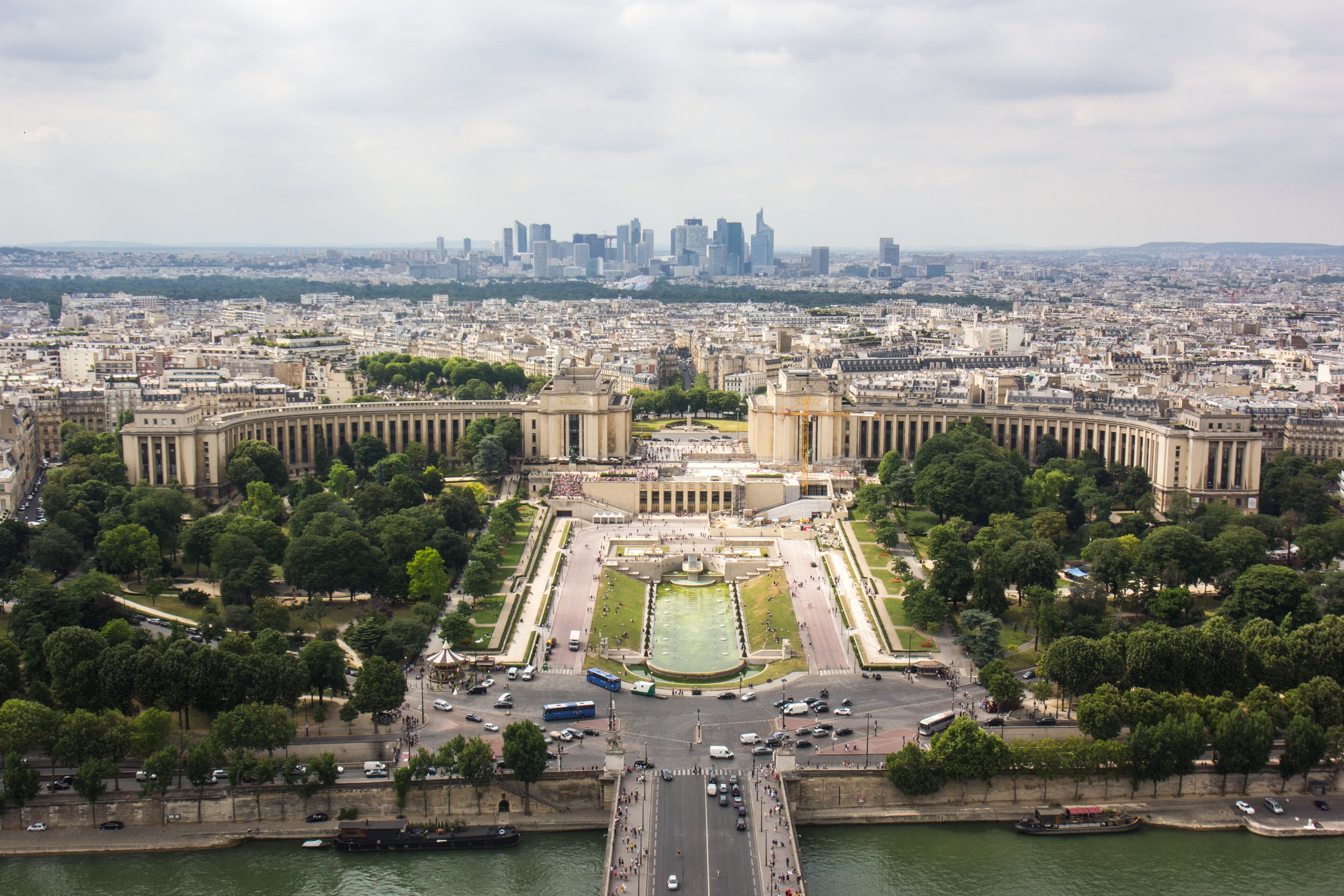 Aerial view of the Trocadéro Gardens and Palace with city skyline in the background, along the riverbank.