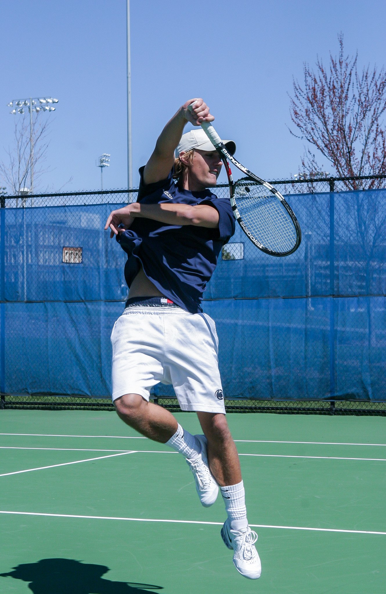 A young man playing tennis on an outdoor court, preparing to hit a shot with his racket.